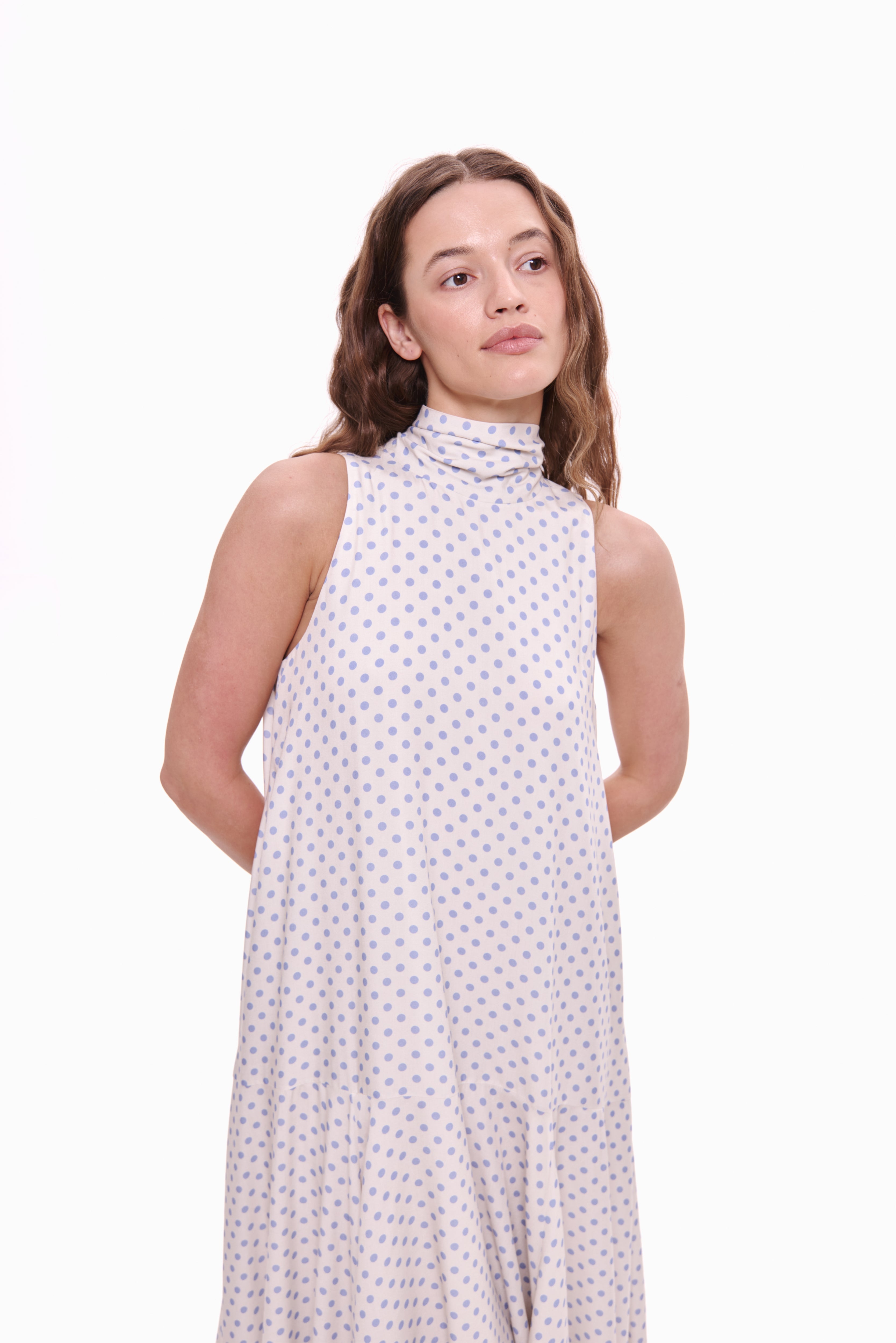 Woman wearing a sleeveless dress with a pattern on a white background