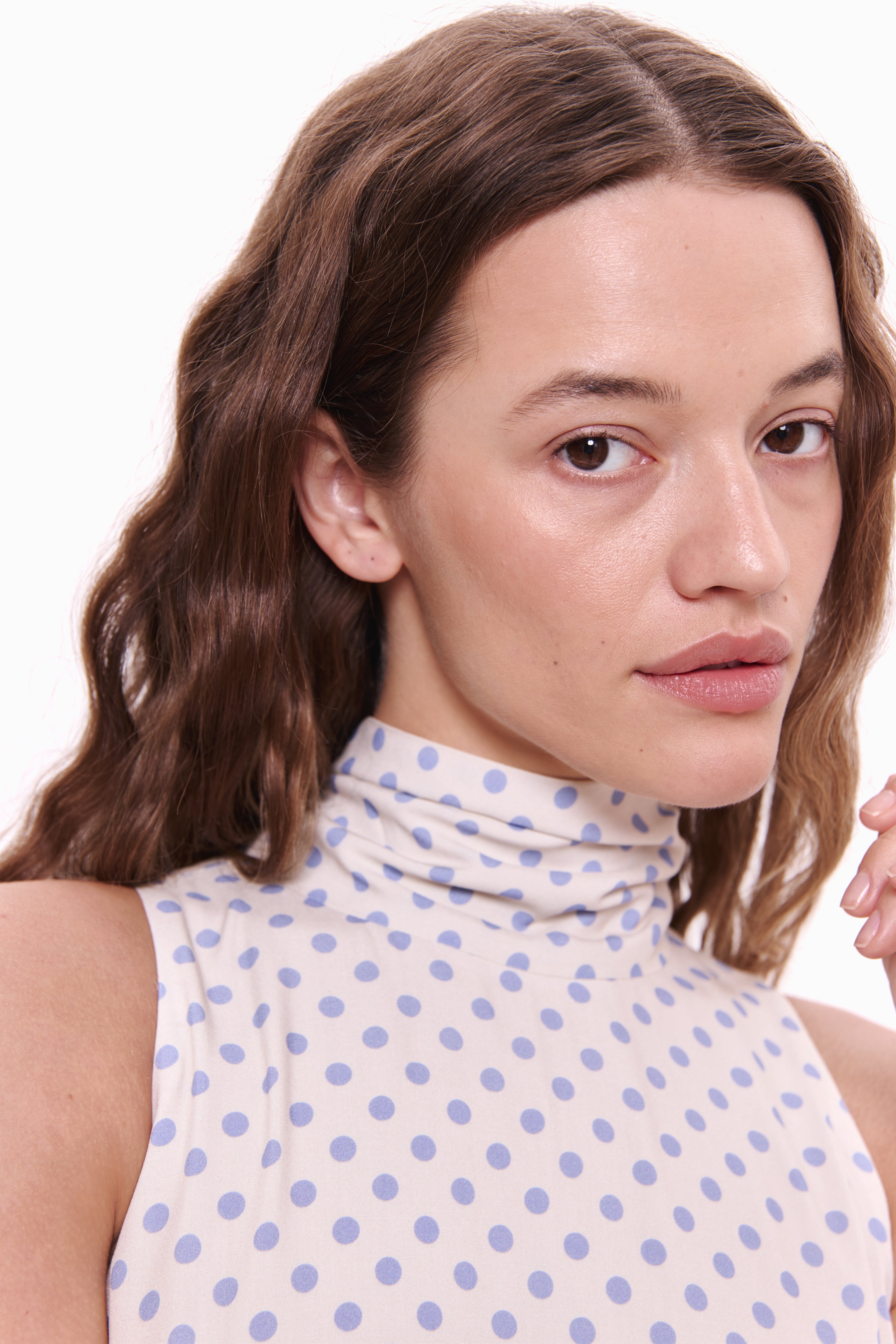 Woman wearing a sleeveless top with a polka dot pattern on a white background