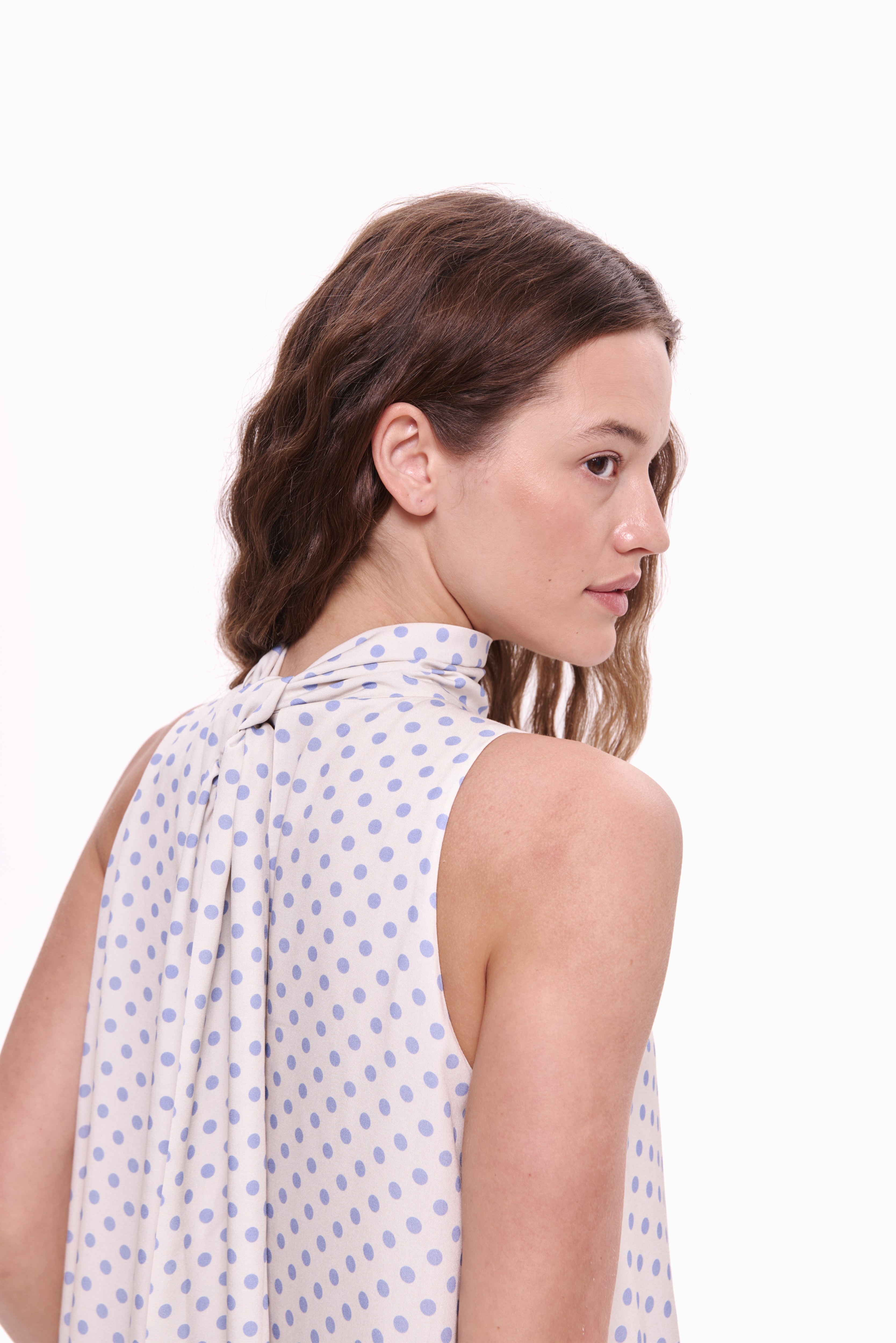 Woman wearing a sleeveless polka dot blouse on a white background