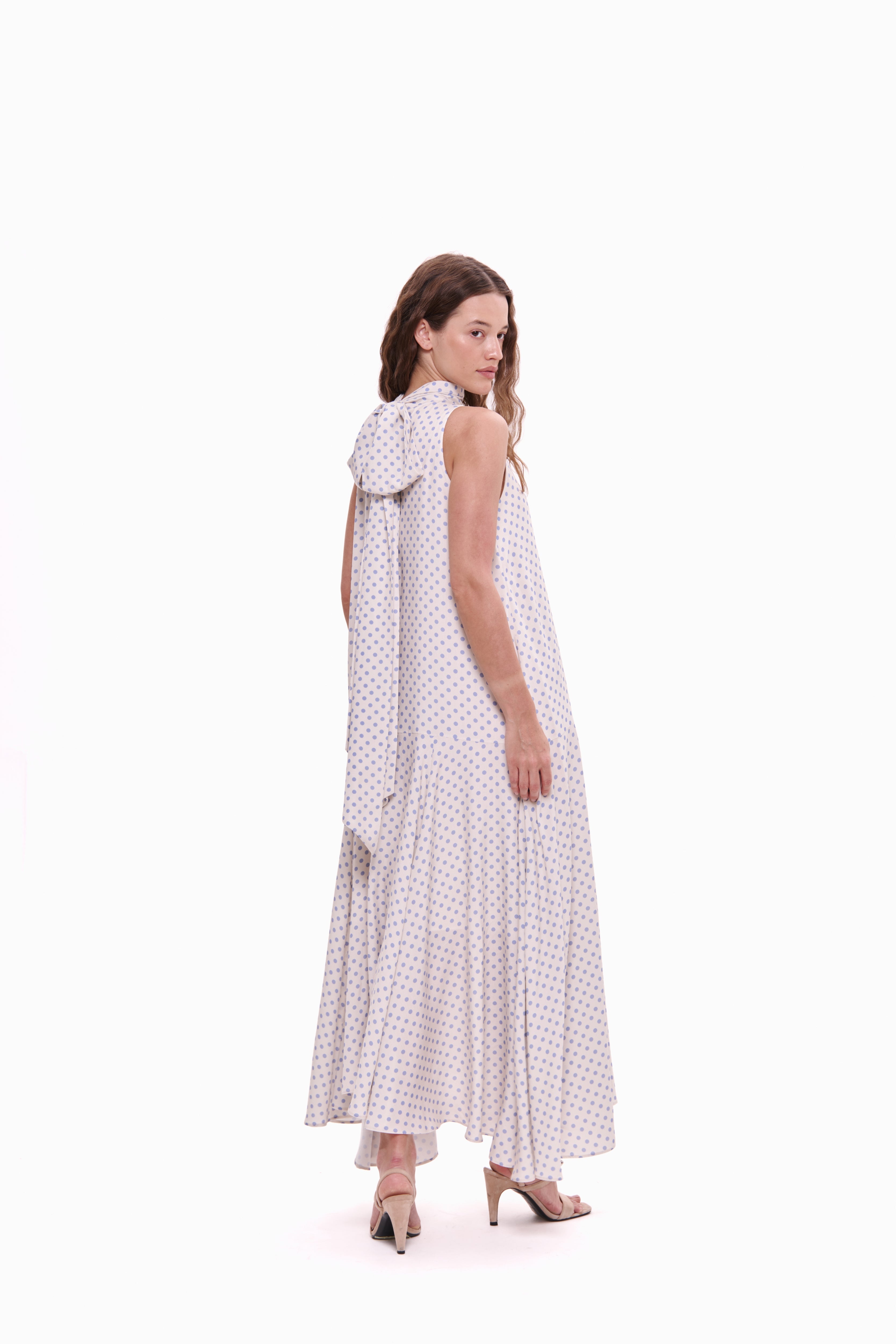 Woman wearing a white dress with black polka dots on a white background