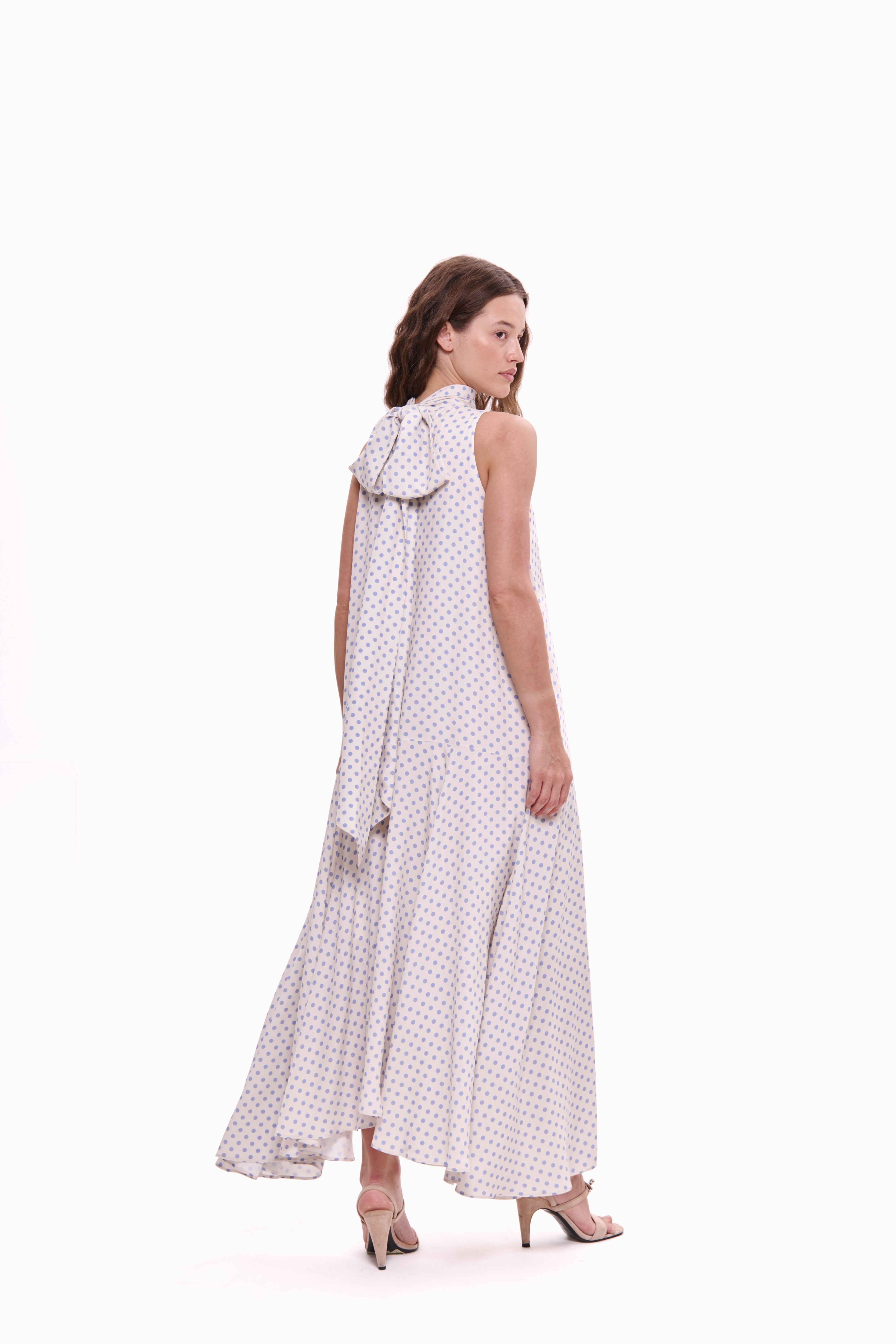Woman wearing a white dress with black polka dots on a white background