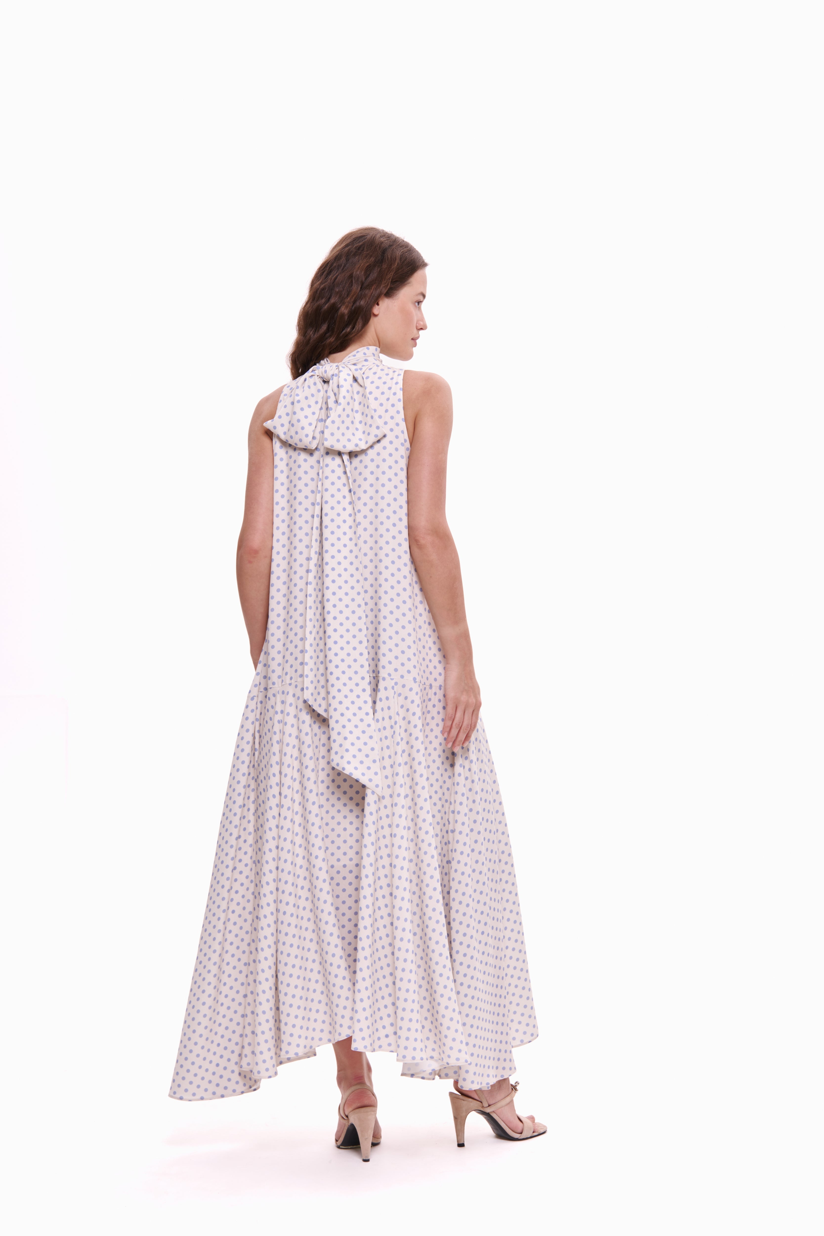 Woman wearing a white dress with black polka dots on a white background