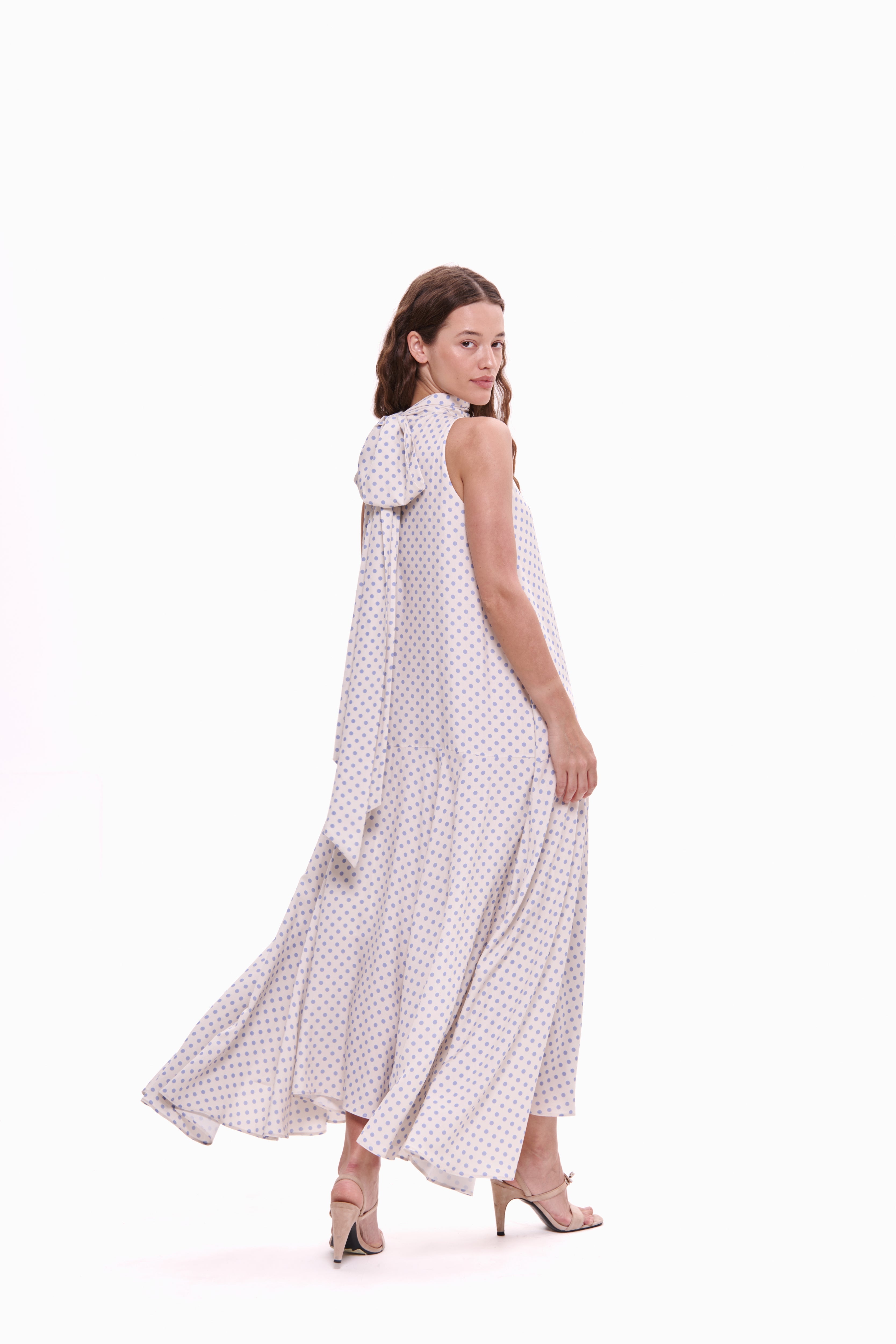Woman wearing a white dress with black polka dots on a white background