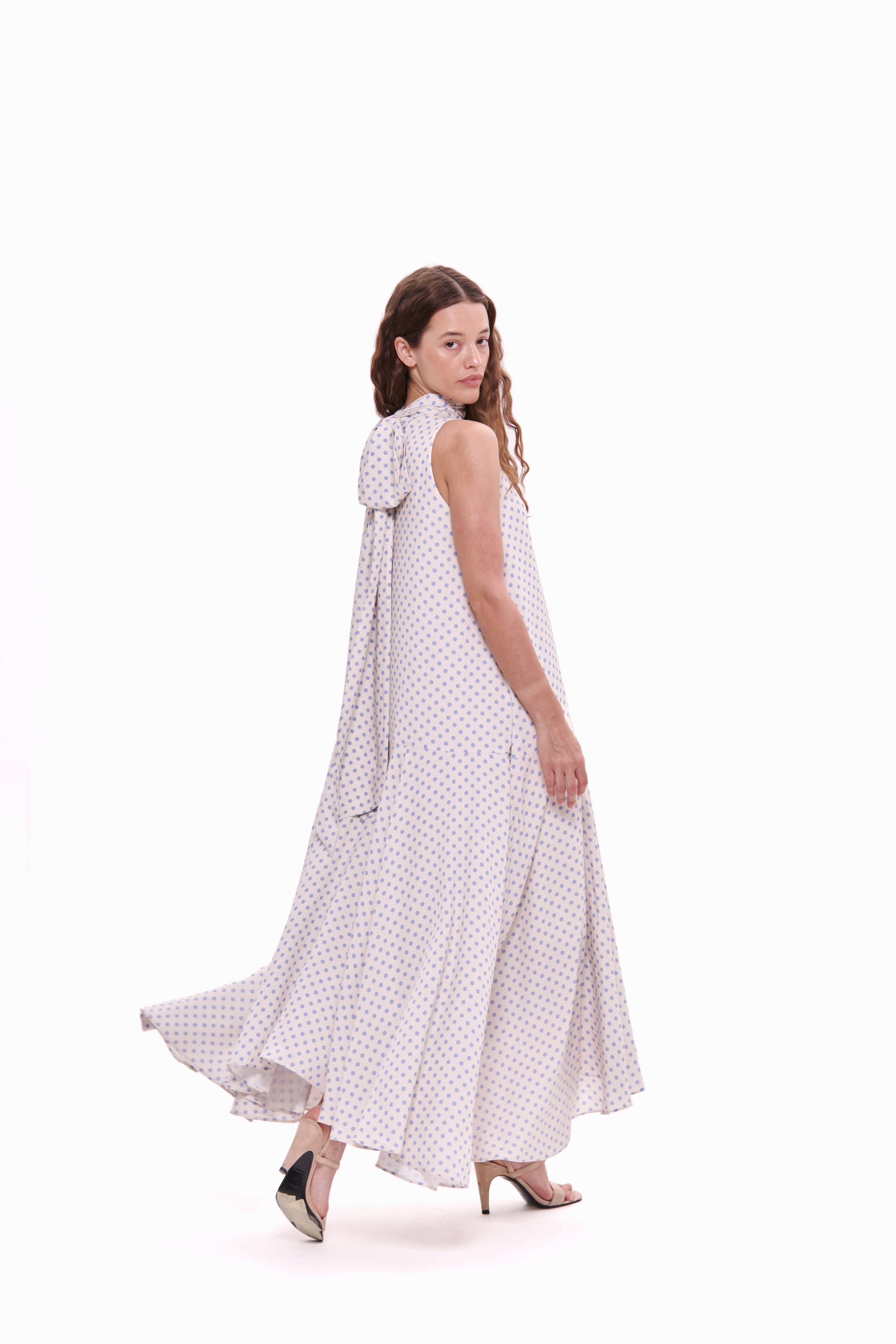 Woman wearing a white dress with black polka dots on a white background