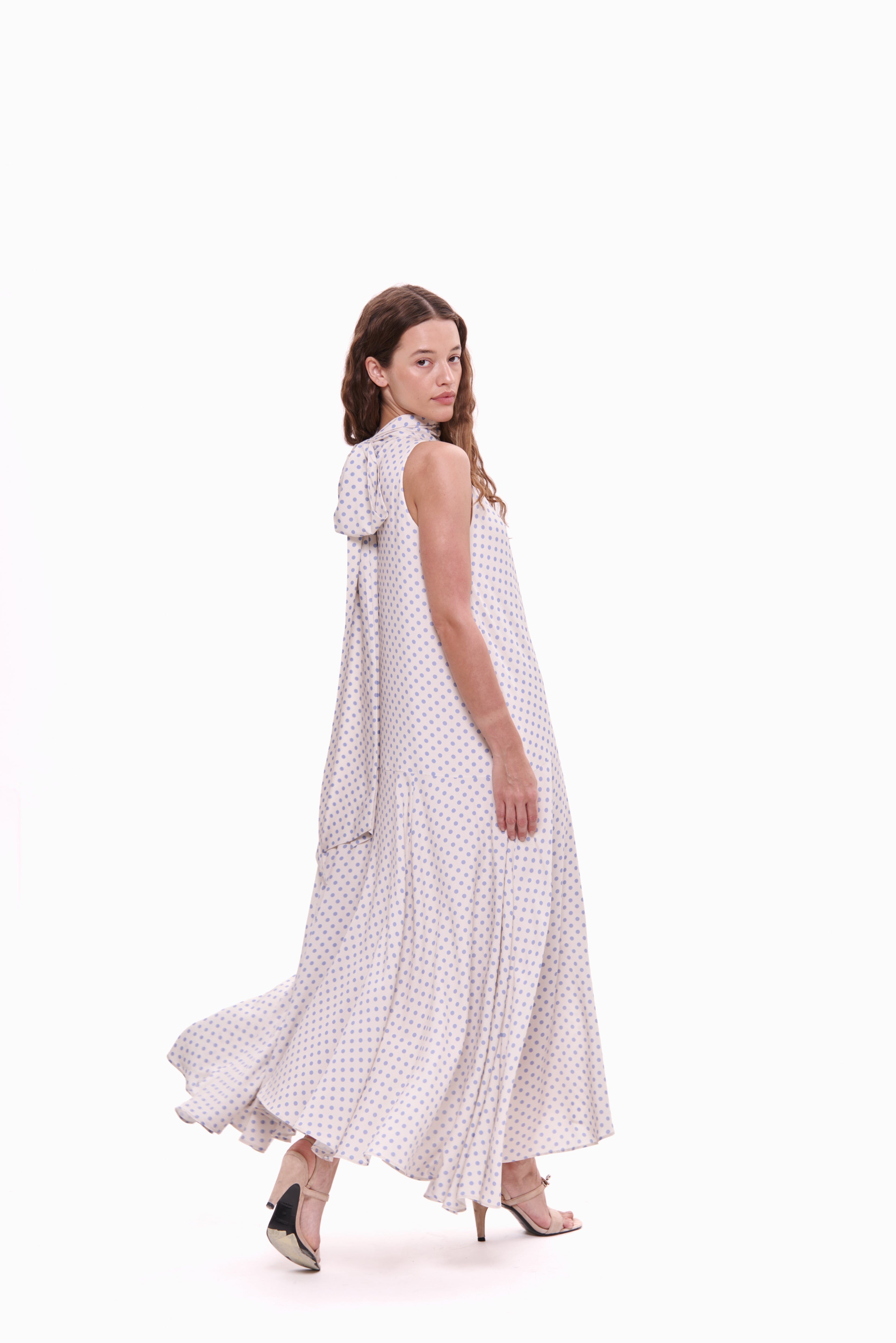 Woman wearing a white dress with black polka dots on a white background