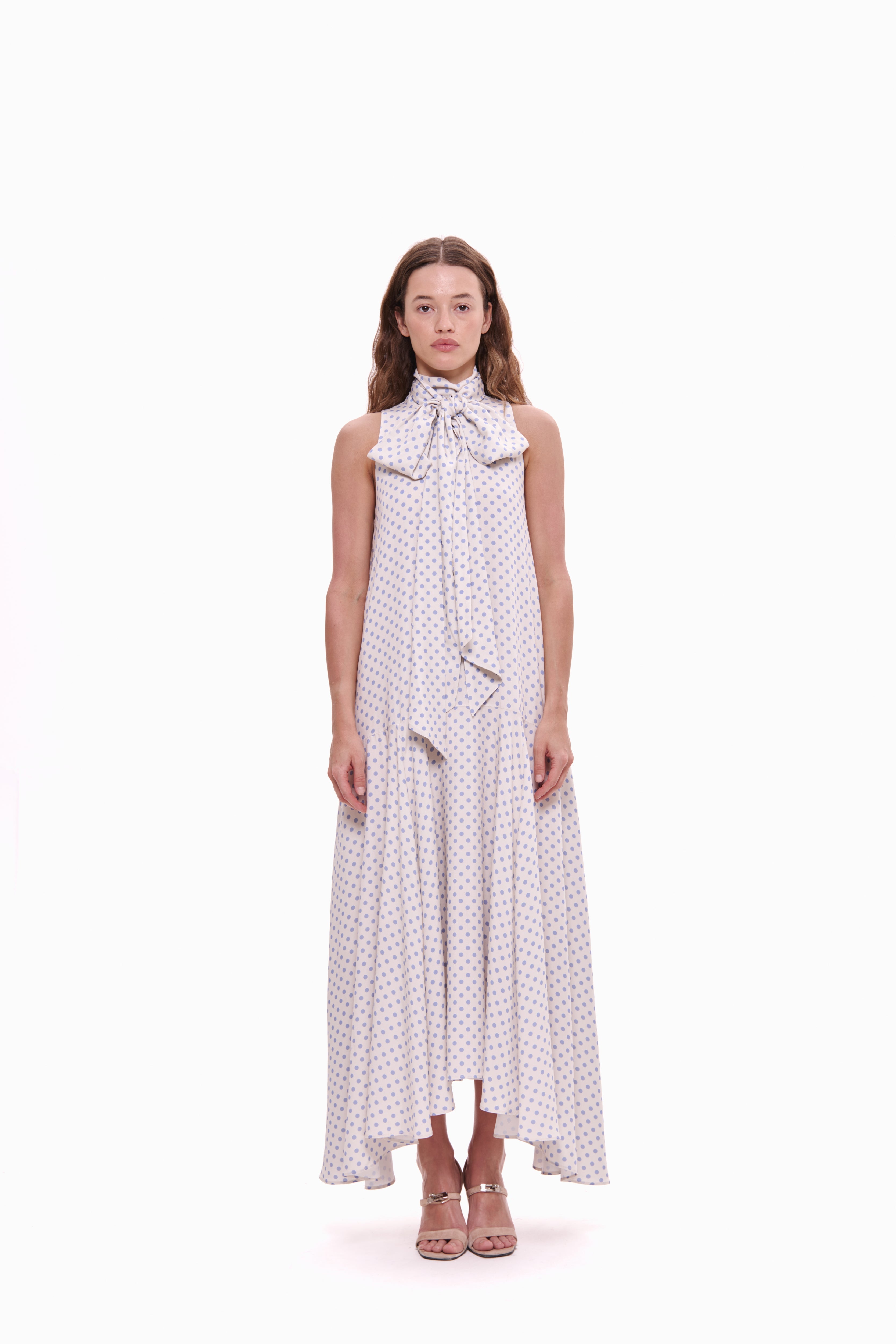 Woman wearing a polka dot dress with a bow tie on a white background