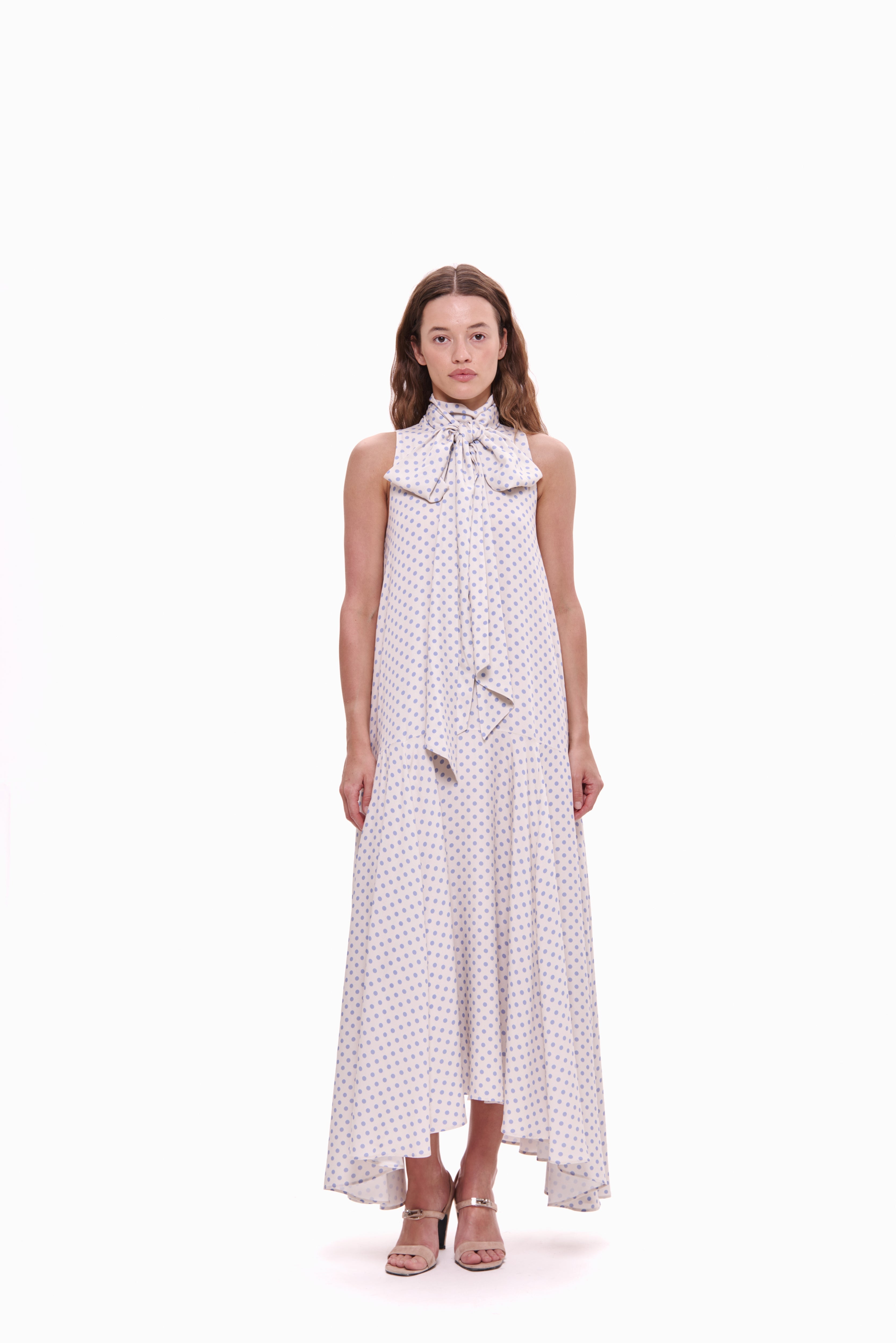 Woman wearing a long, patterned dress with a bow detail on a white background