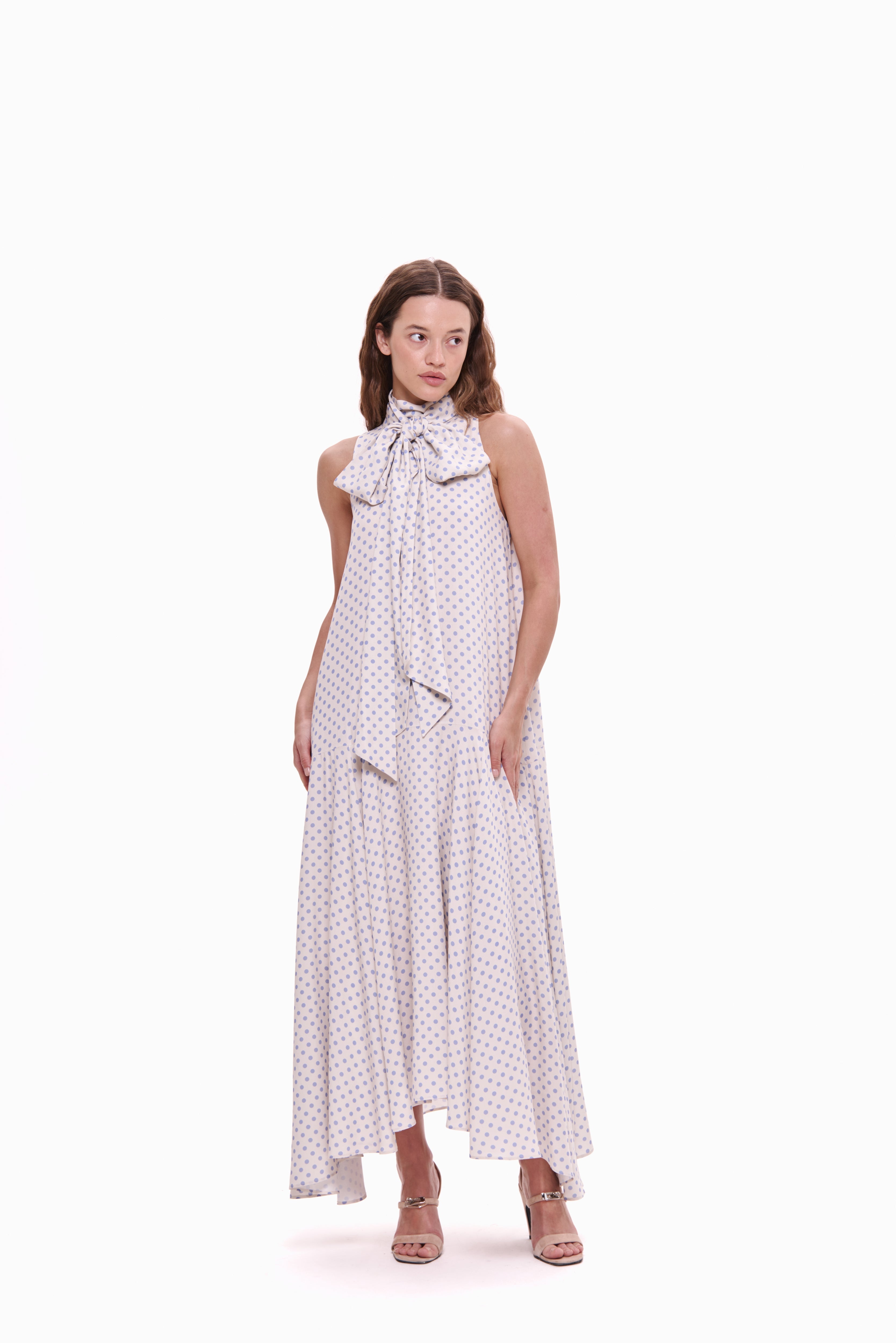Woman wearing a white dress with black polka dots on a white background
