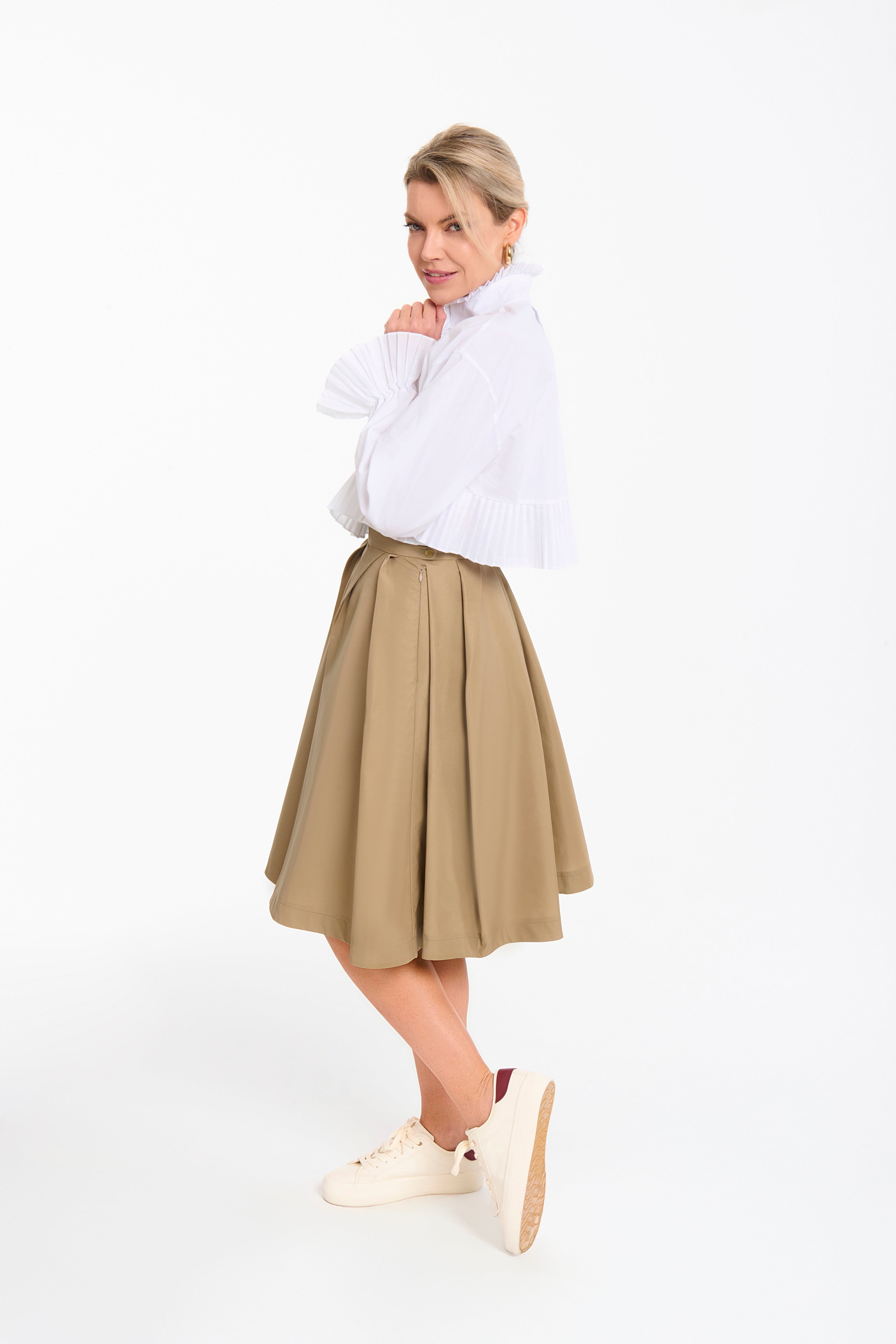 Woman wearing a Mademoiselle Plissé cropped shirt-blouse from Mimaussy Paris, beige pleated skirt, on a white background