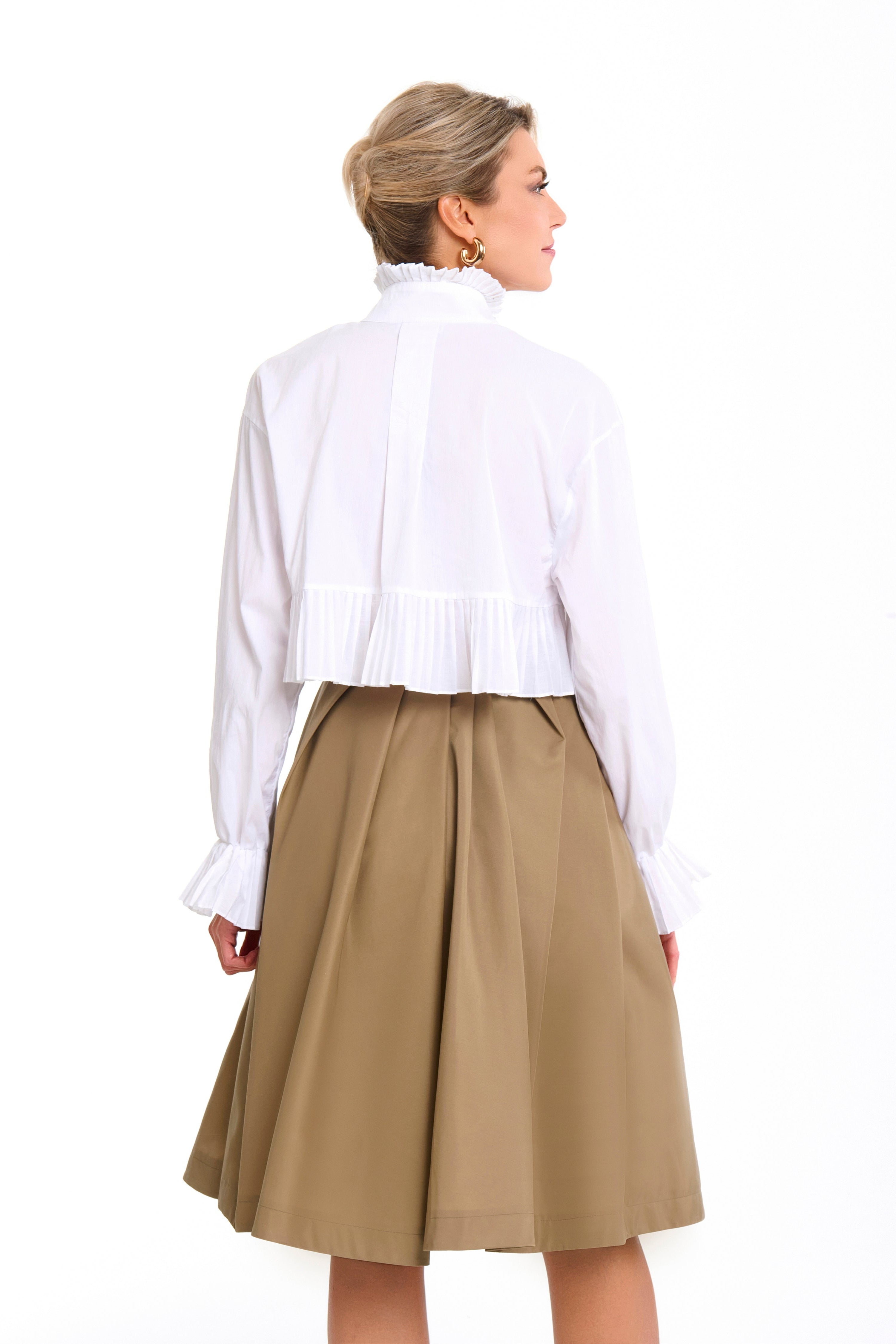 Woman wearing a Mademoiselle Plissé cropped shirt-blouse from Mimaussy Paris, beige skirt, on a white background