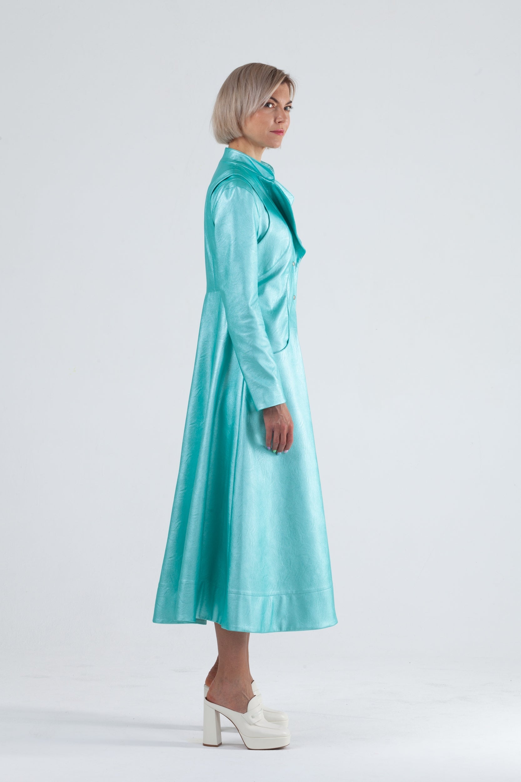 Woman wearing Matrix Coat from Mimaussy Paris in Tiffany Blue, side view full-length shot in studio setting against a plain white background