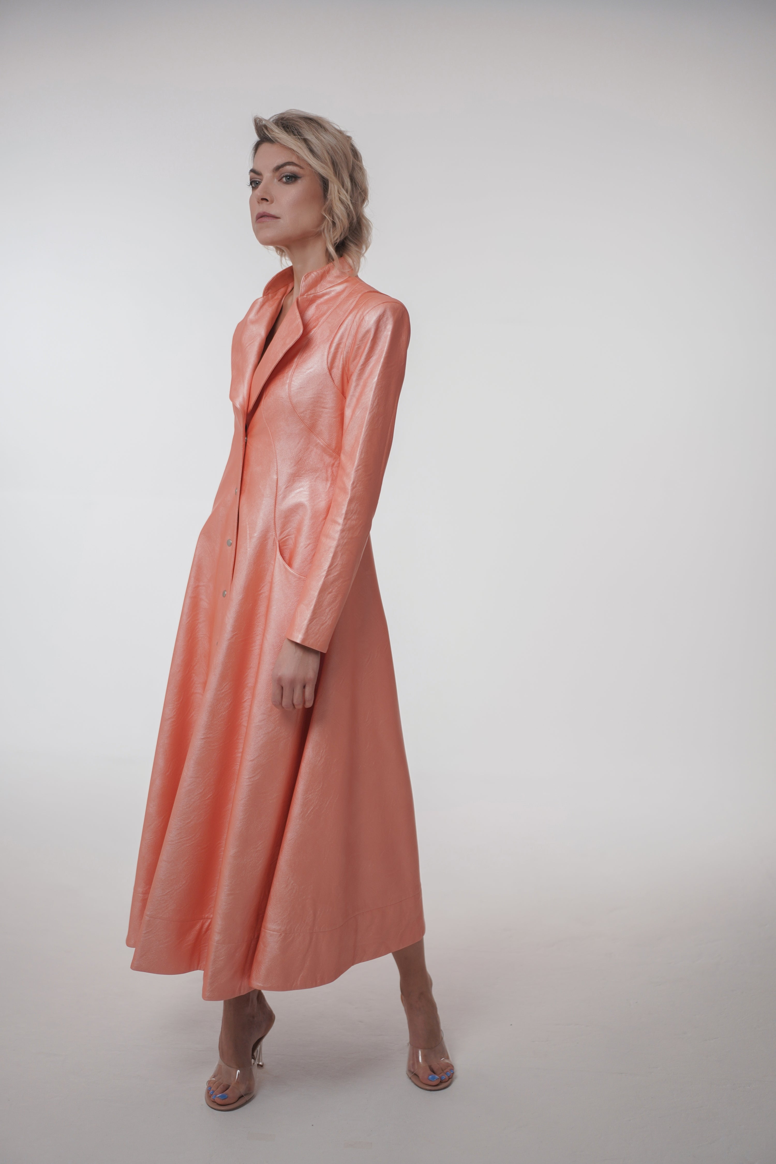 Woman wearing Matrix Coat from Mimaussy Paris in pink, long silhouette, front view in studio setting against a plain white background