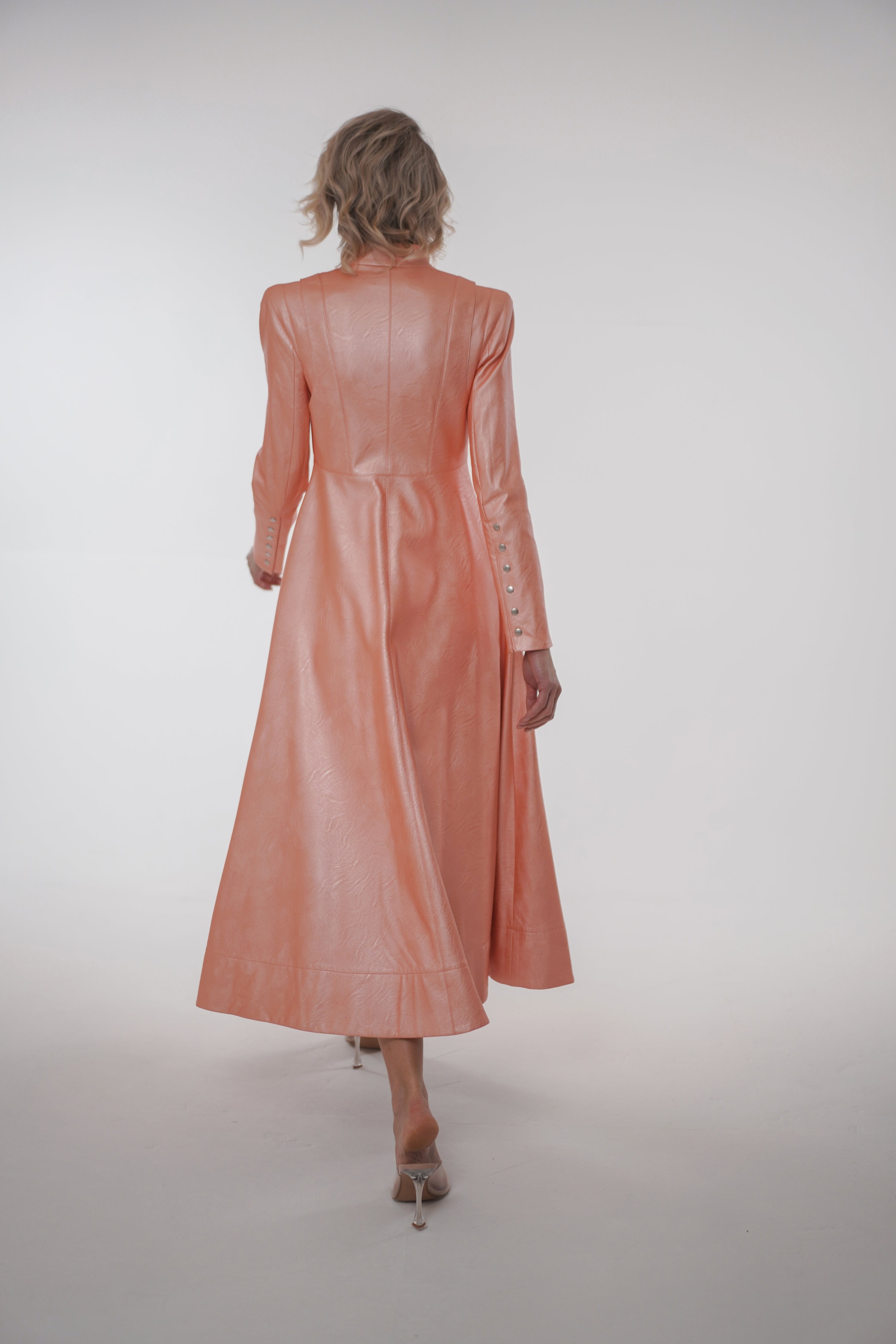Woman wearing Matrix Coat from Mimaussy Paris in light pink, back view full-length shot in studio setting against a plain white background