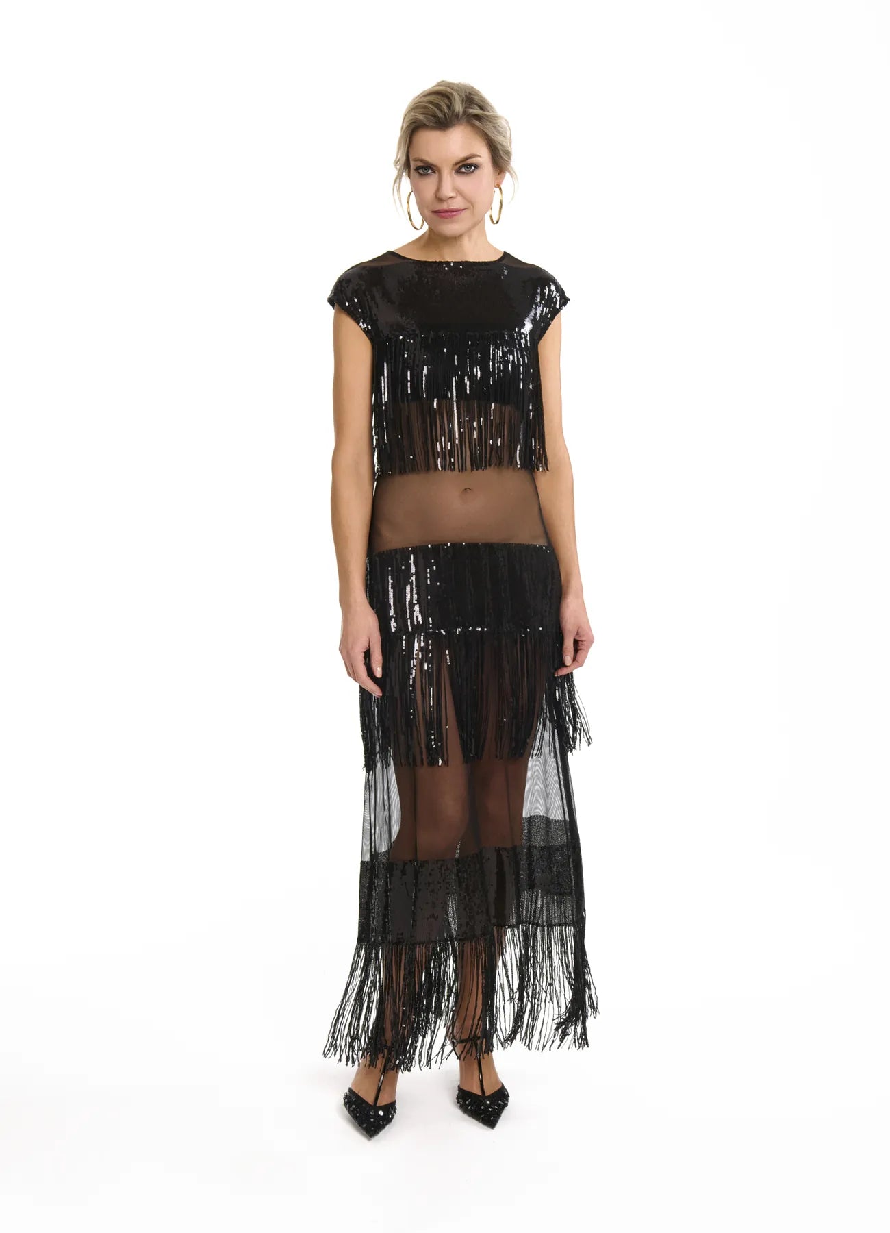 A woman wears the Midnight Charleston Dress in Black Diamond, a black sequin dress crafted from sheer mesh and netting.