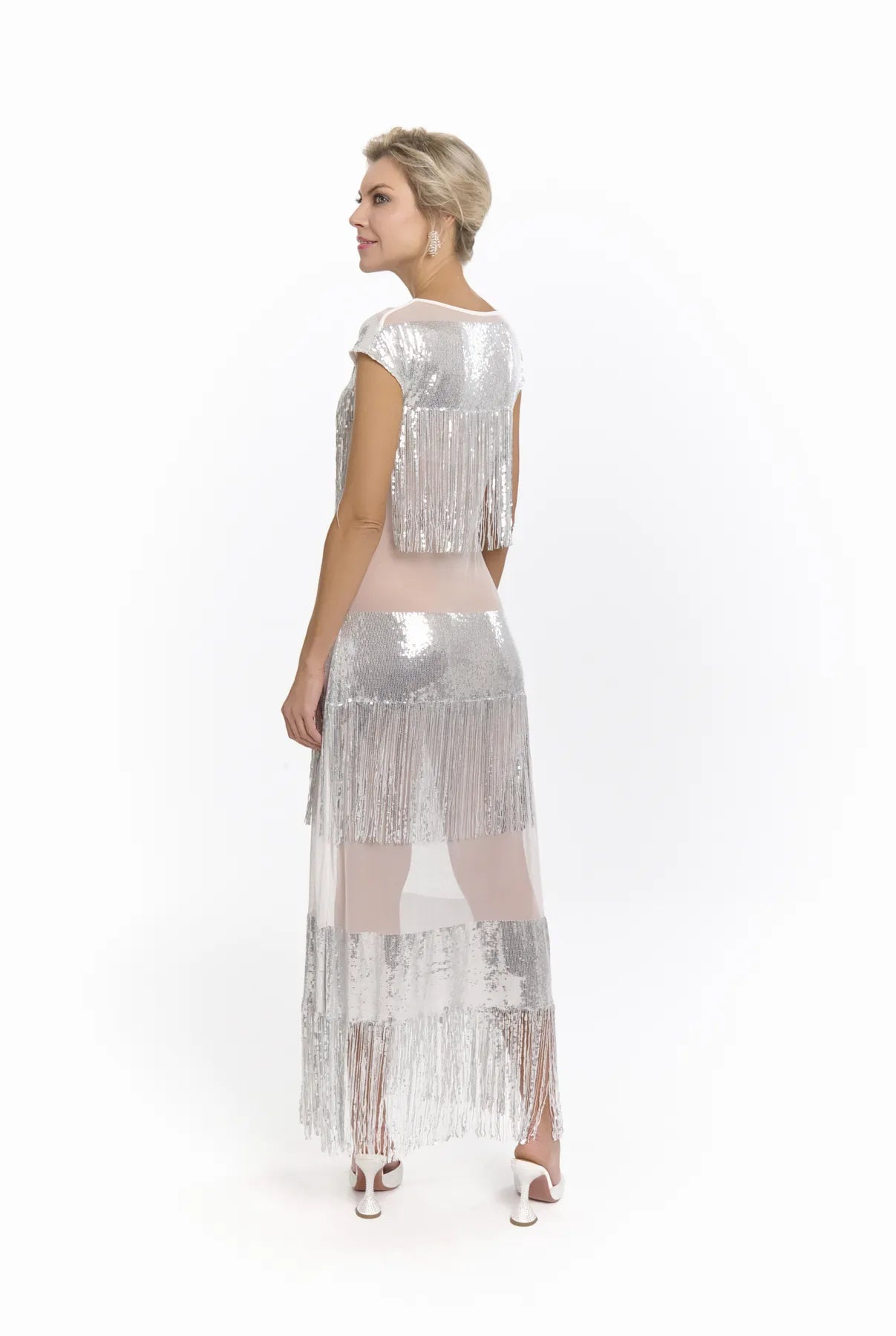 A woman in a silver dress by Mimaussy Paris poses for a photo, highlighting the chic design of the Midnight Charleston Dress.