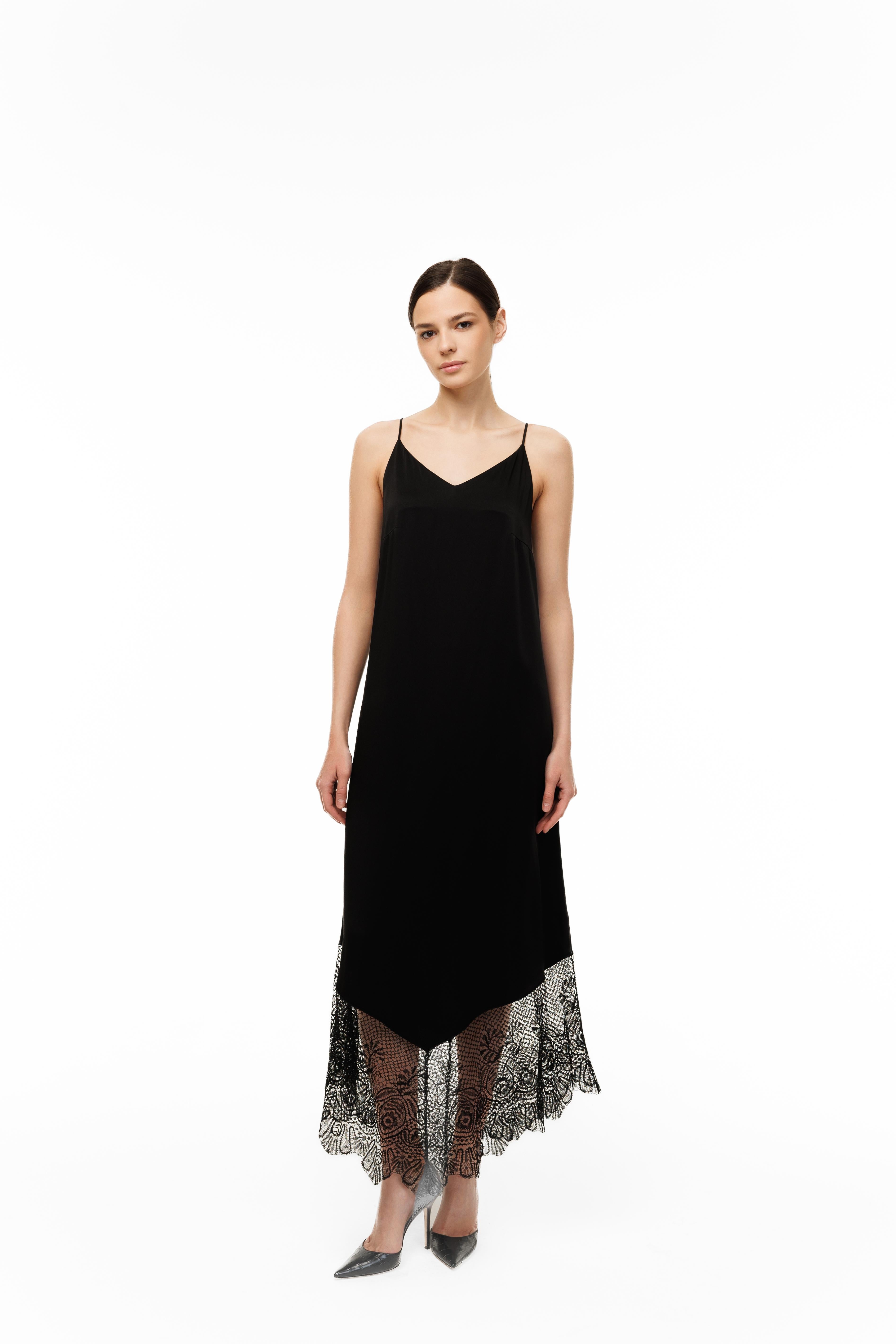 Woman wearing a black slip dress with lace hem on a white background