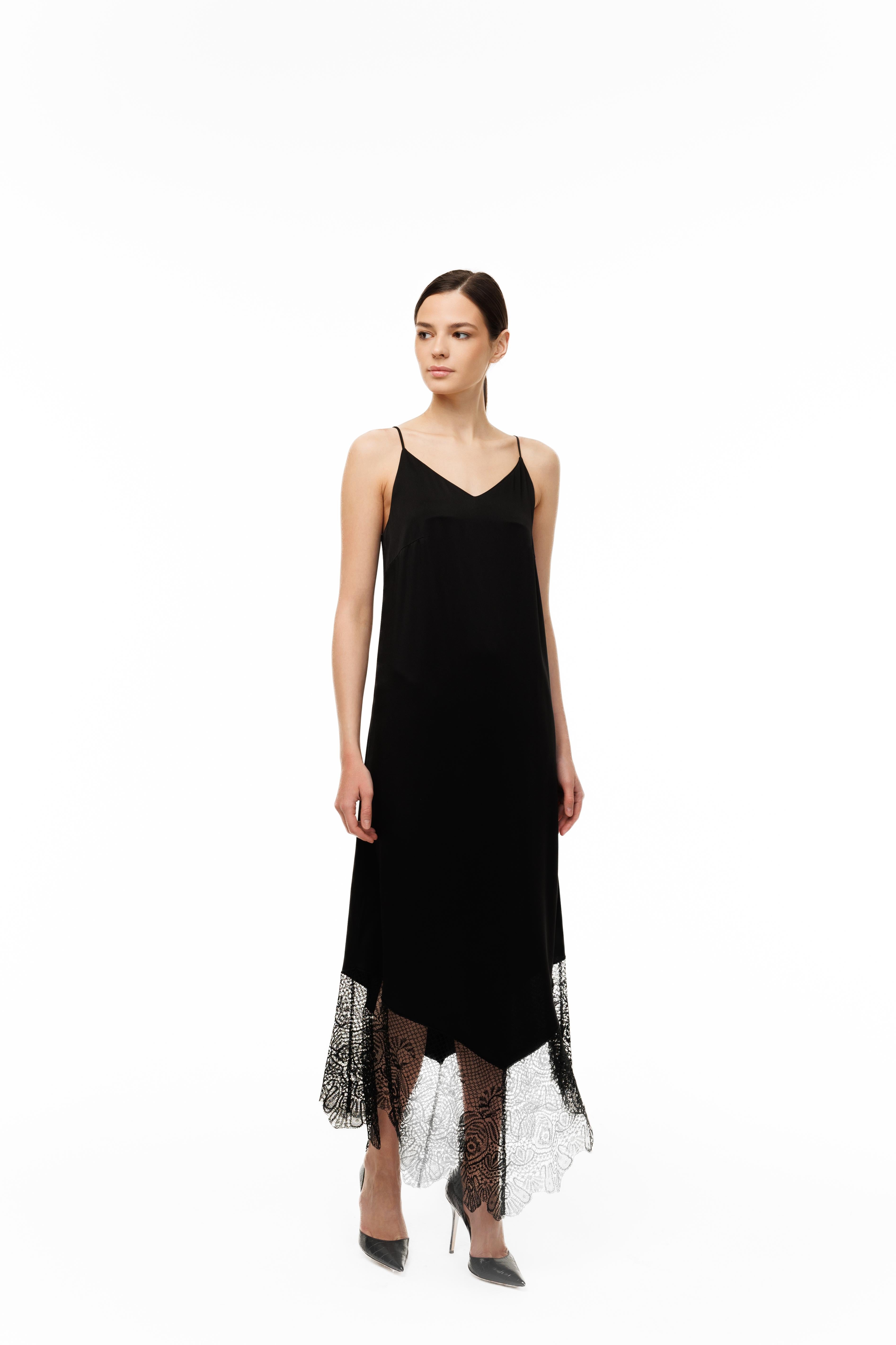 Woman wearing a black slip dress with sheer overlay on a white background