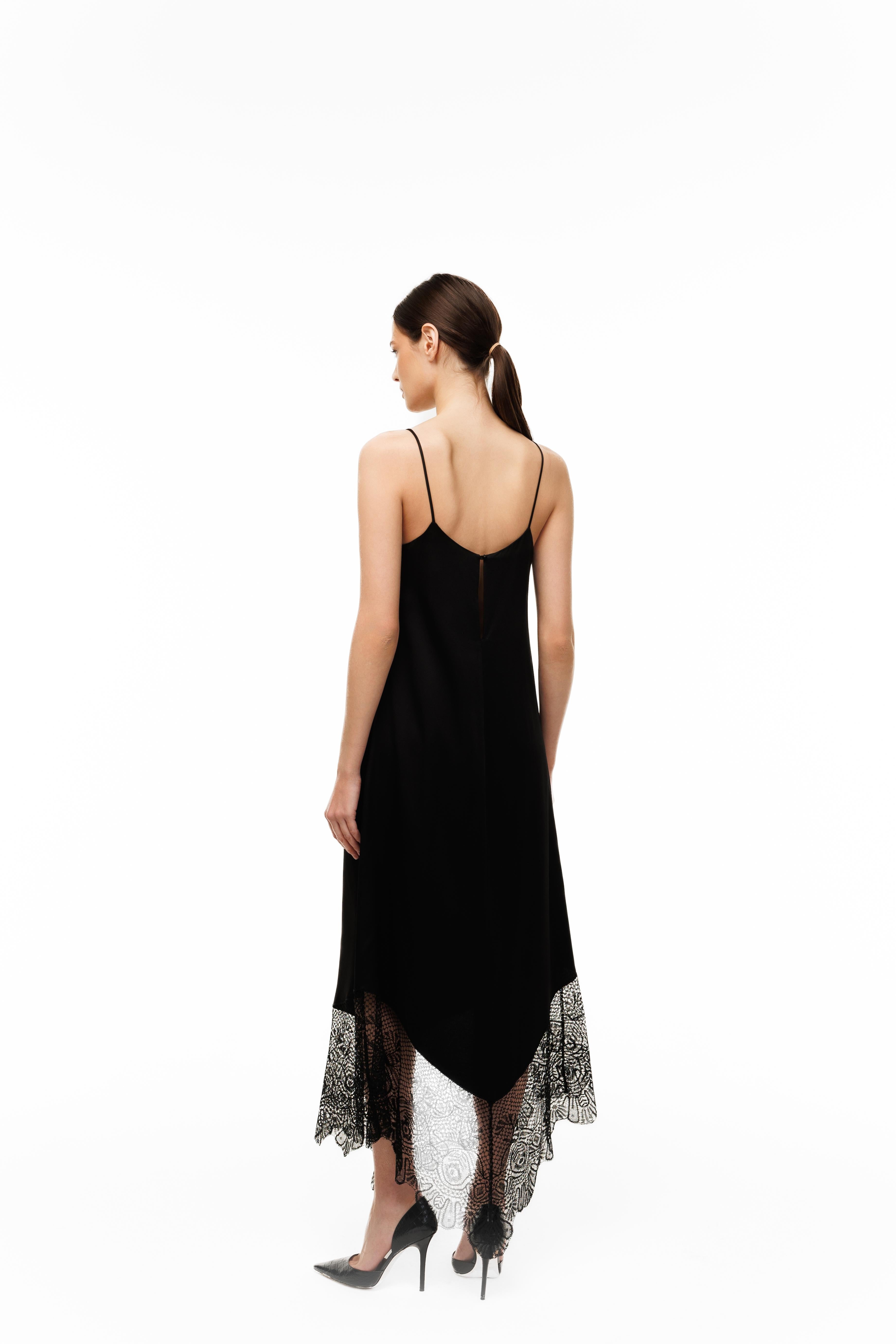 Woman wearing a black slip dress with lace trim on a white background