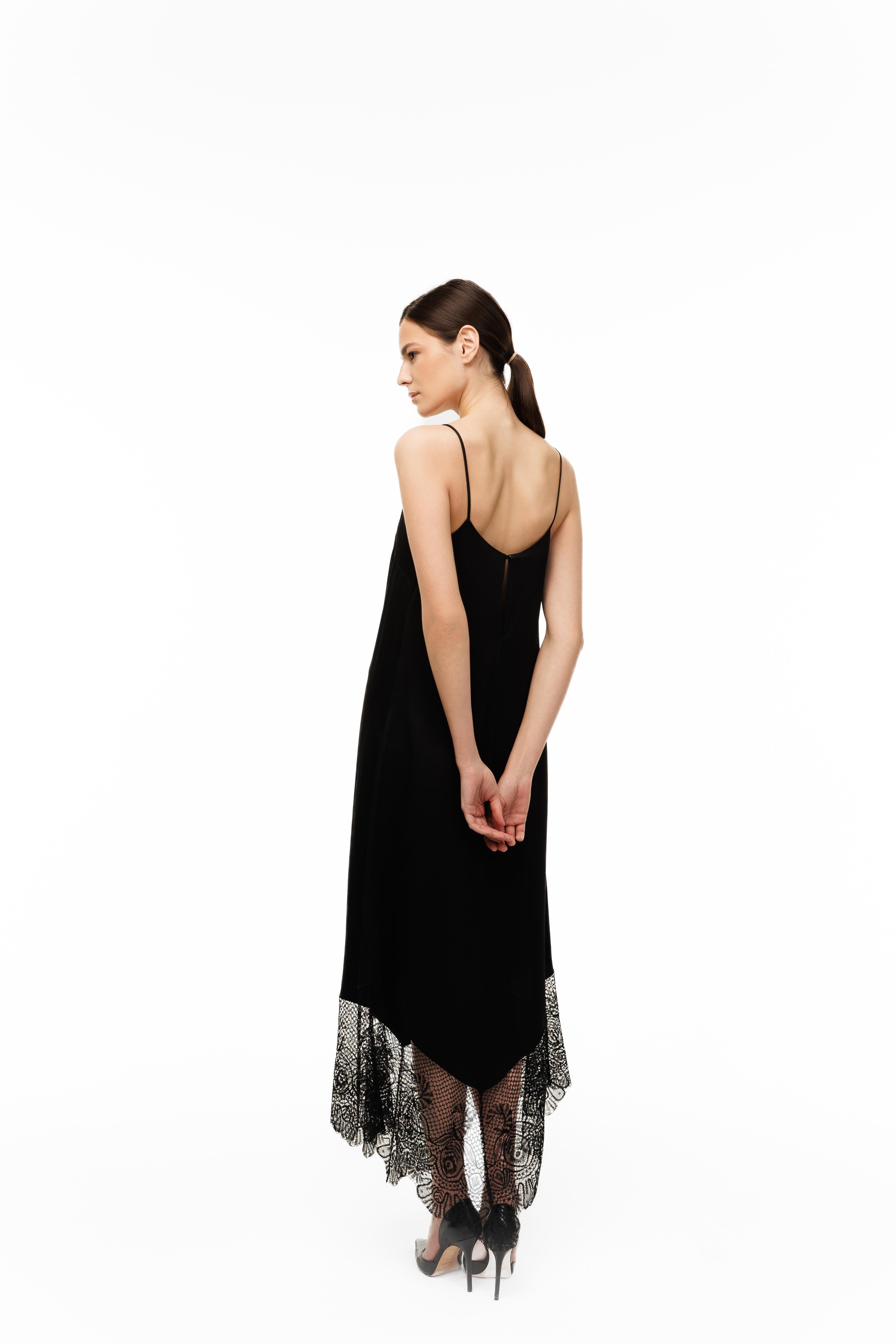 Woman wearing a black dress with sheer overlay on a white background