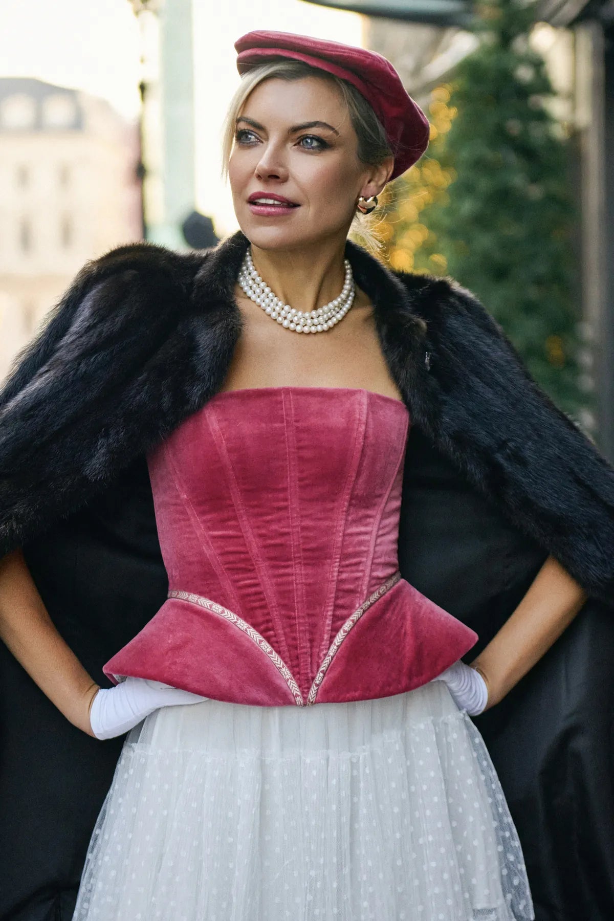 A woman in a red corset and fur coat, showcasing the Mystery Velvet Corset from Mimaussy Paris.