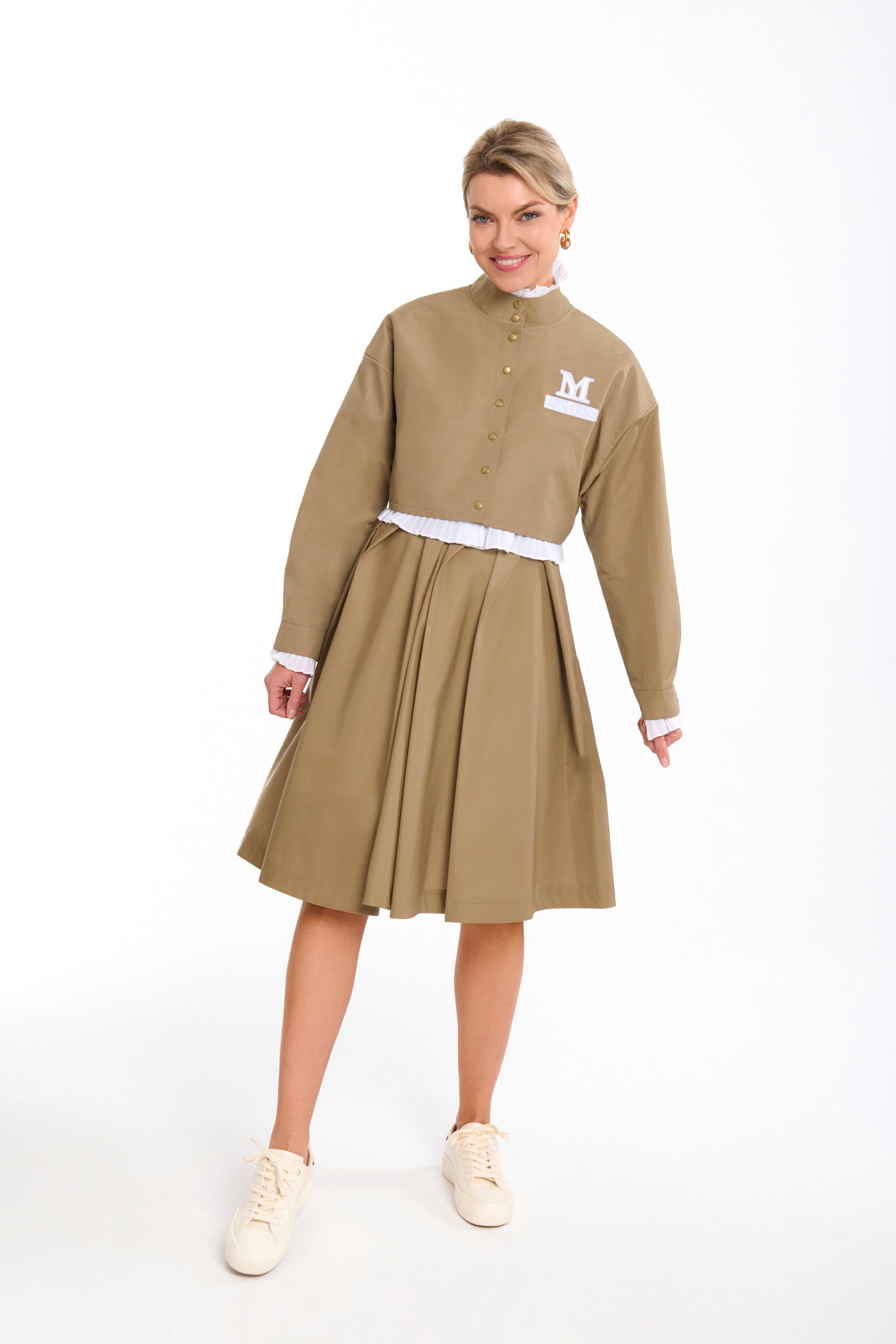 Woman wearing a Parisien Cropped Trench Jacket from Mimaussy Paris, beige dress with white collar and cuffs, on a white background