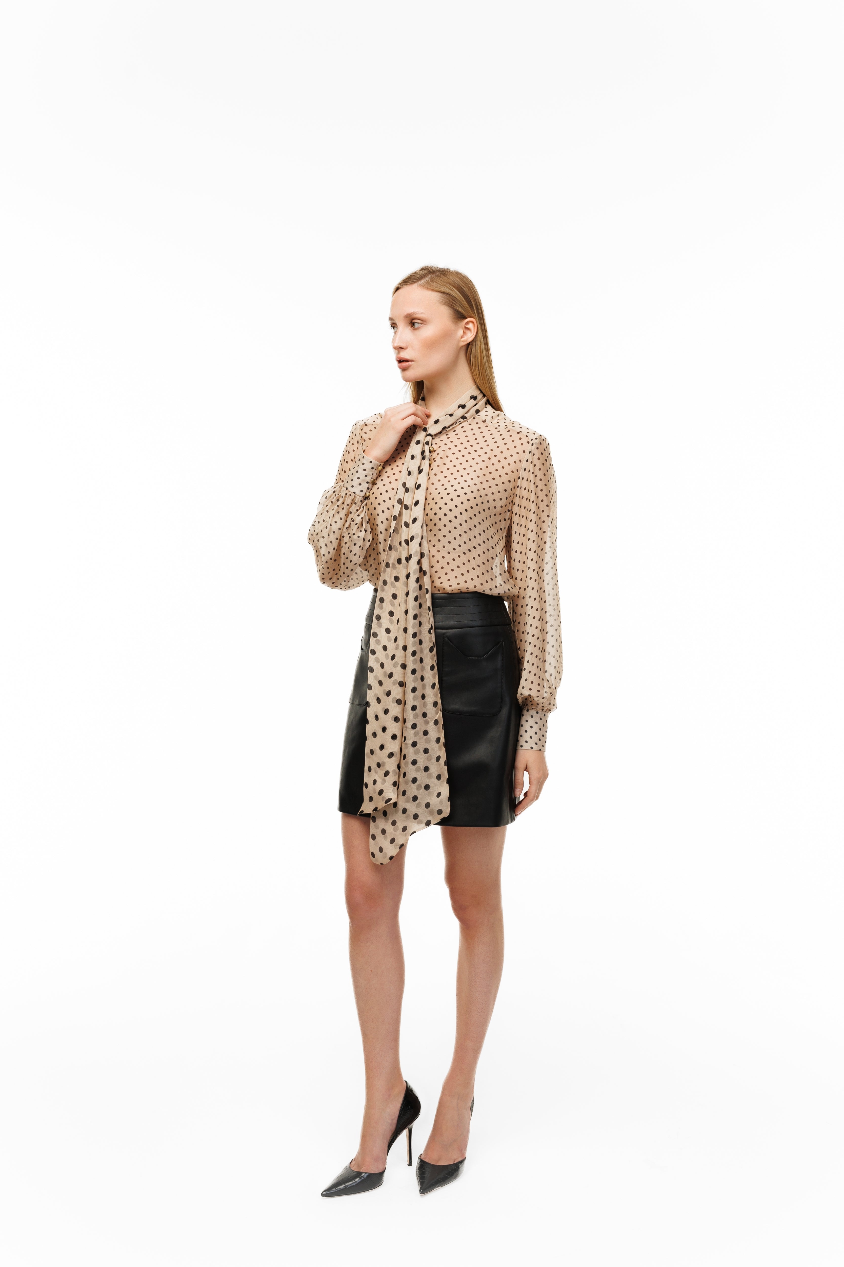 Woman wearing a patterned blouse and black skirt on a white background