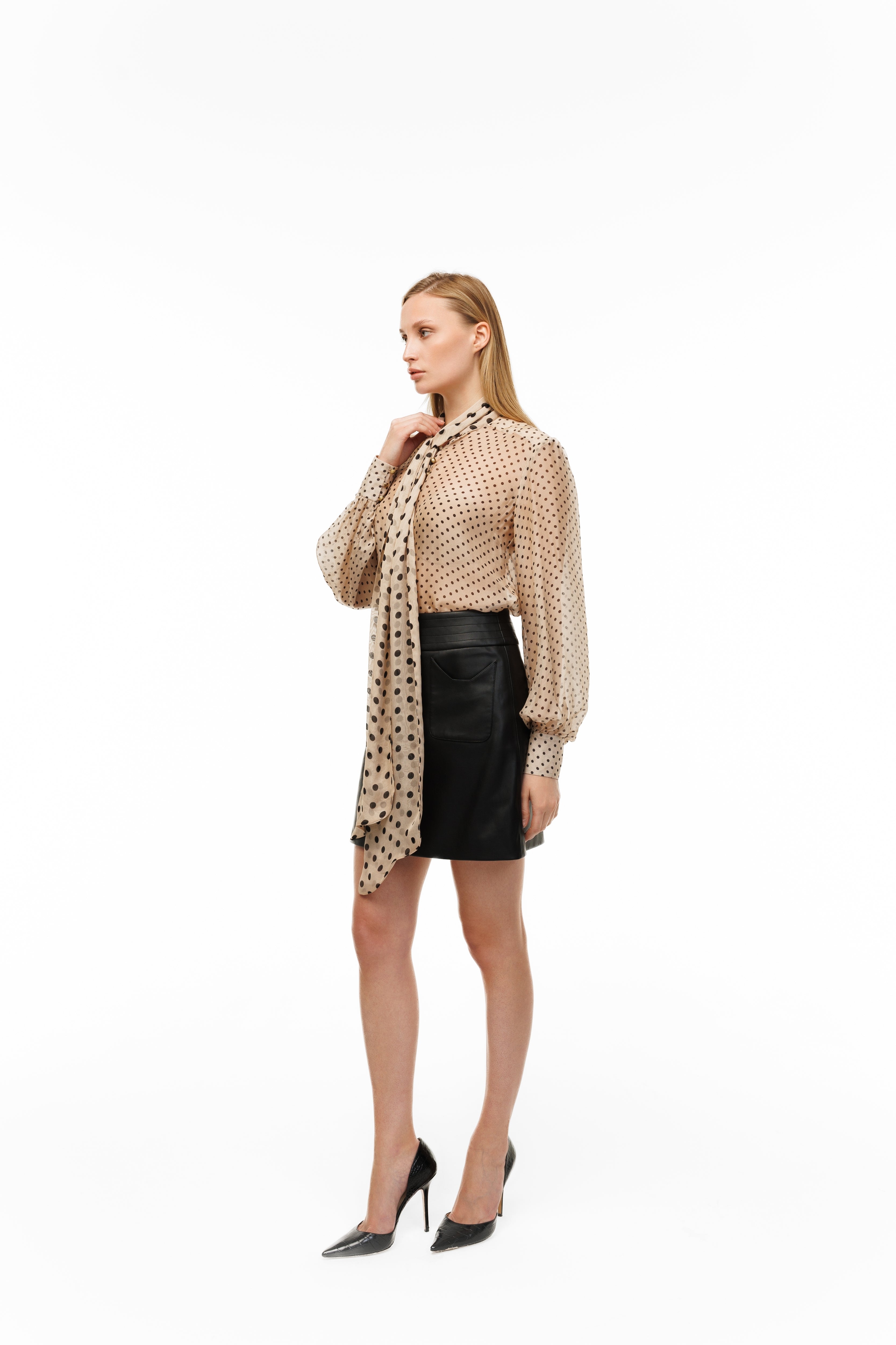 Woman wearing a patterned blouse and black skirt on a white background