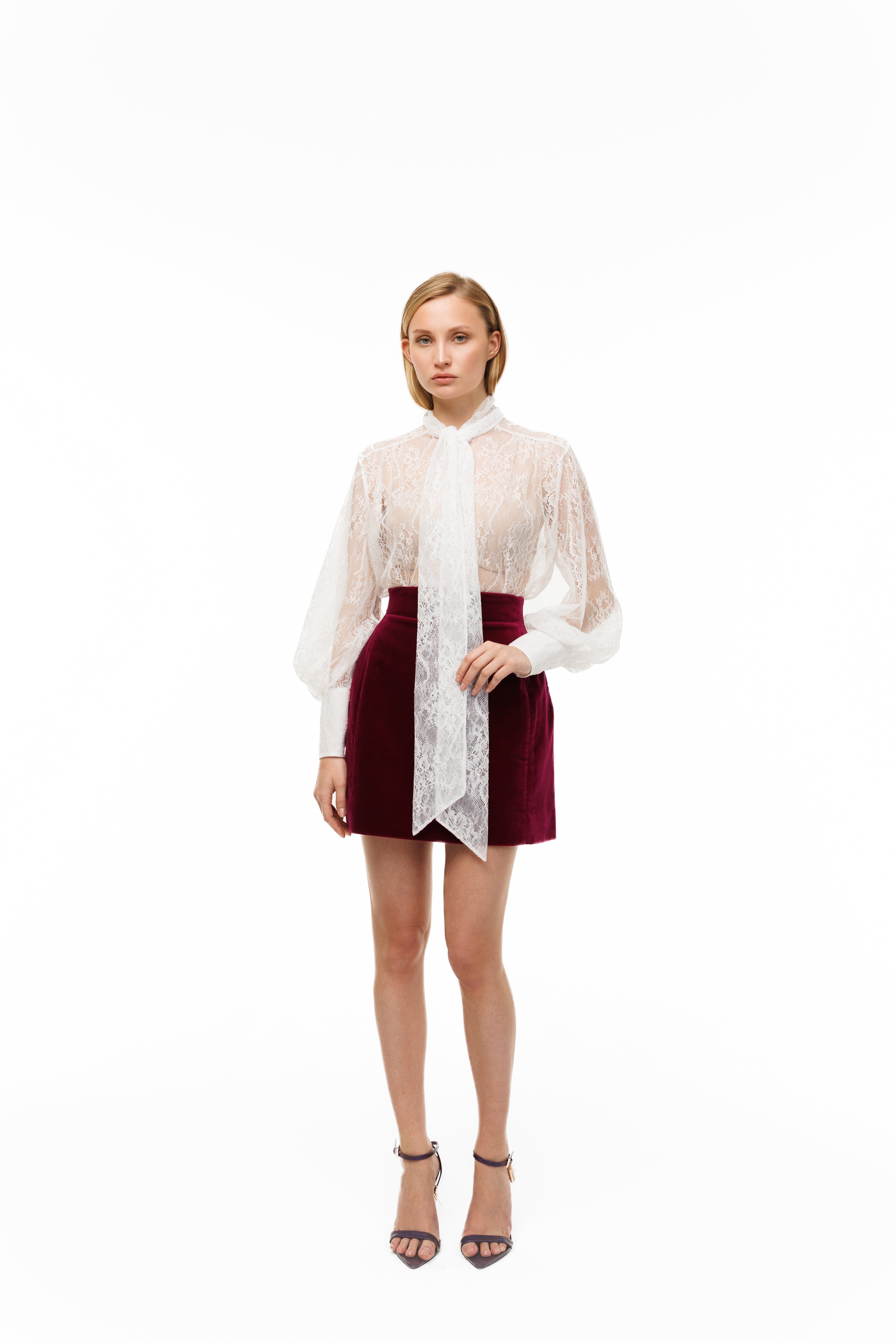 Woman wearing a white lace blouse over a red dress on a white background