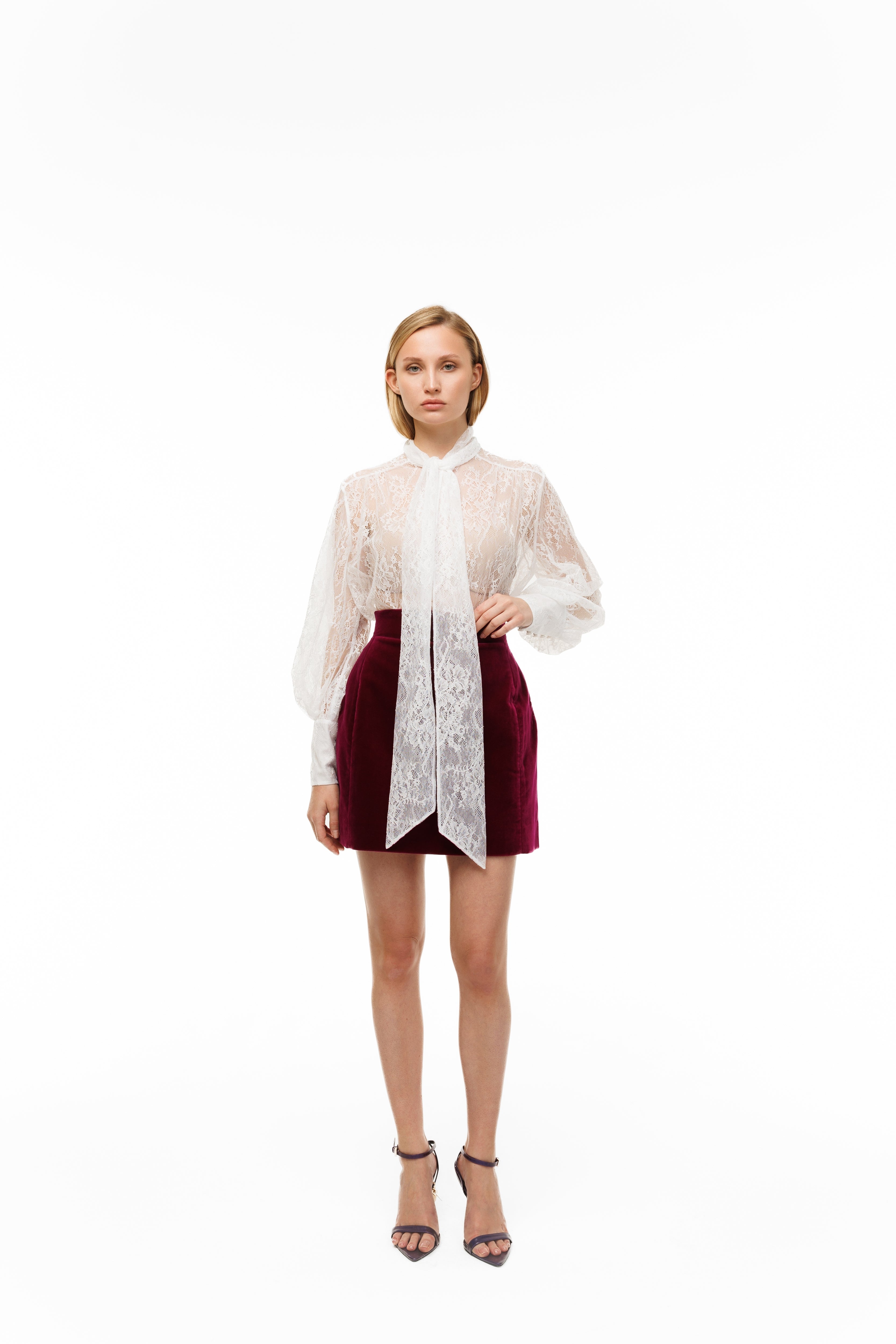 Woman wearing a white lace blouse and red skirt on a white background