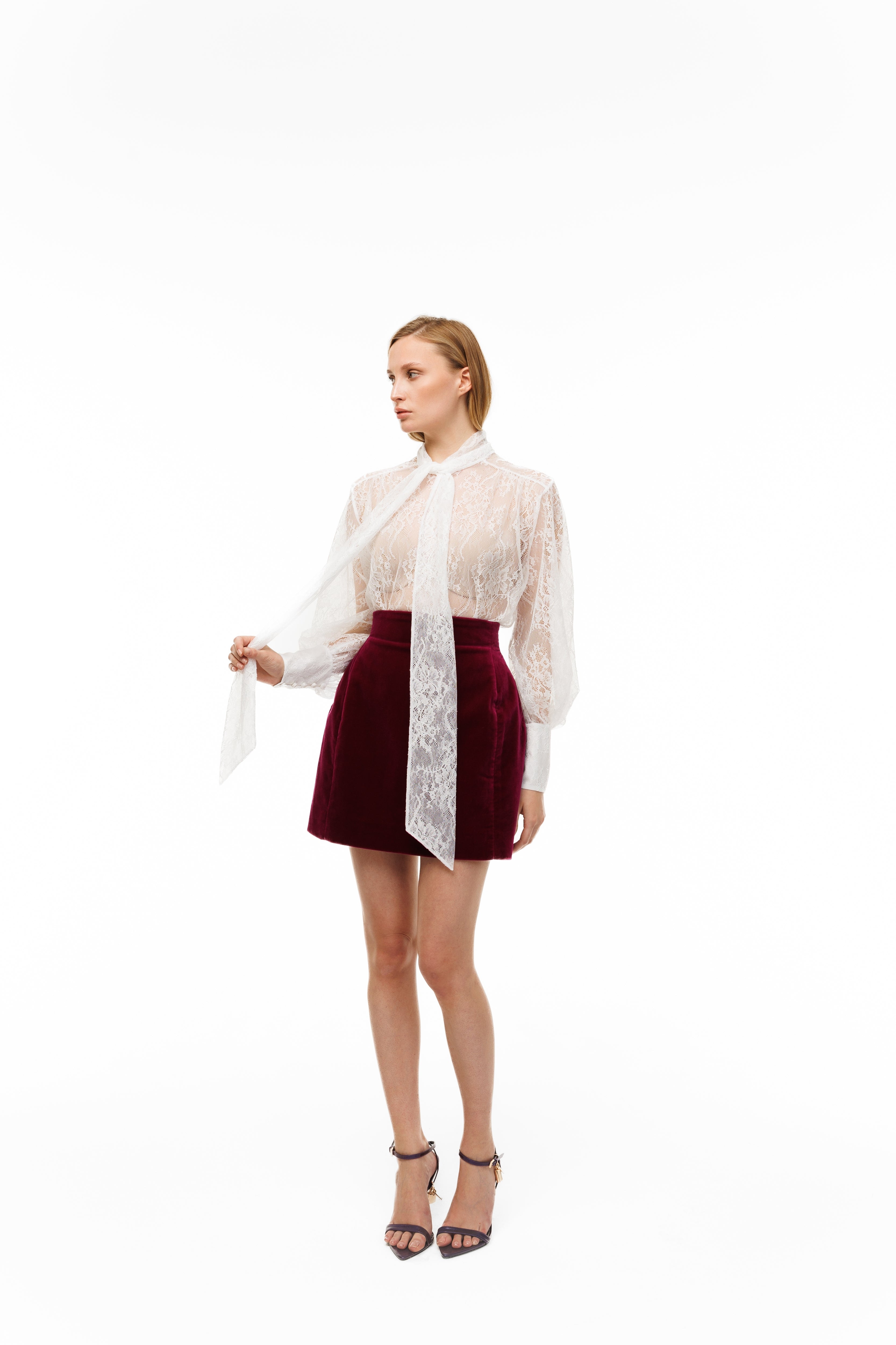 Woman wearing a white lace blouse and red skirt on a white background