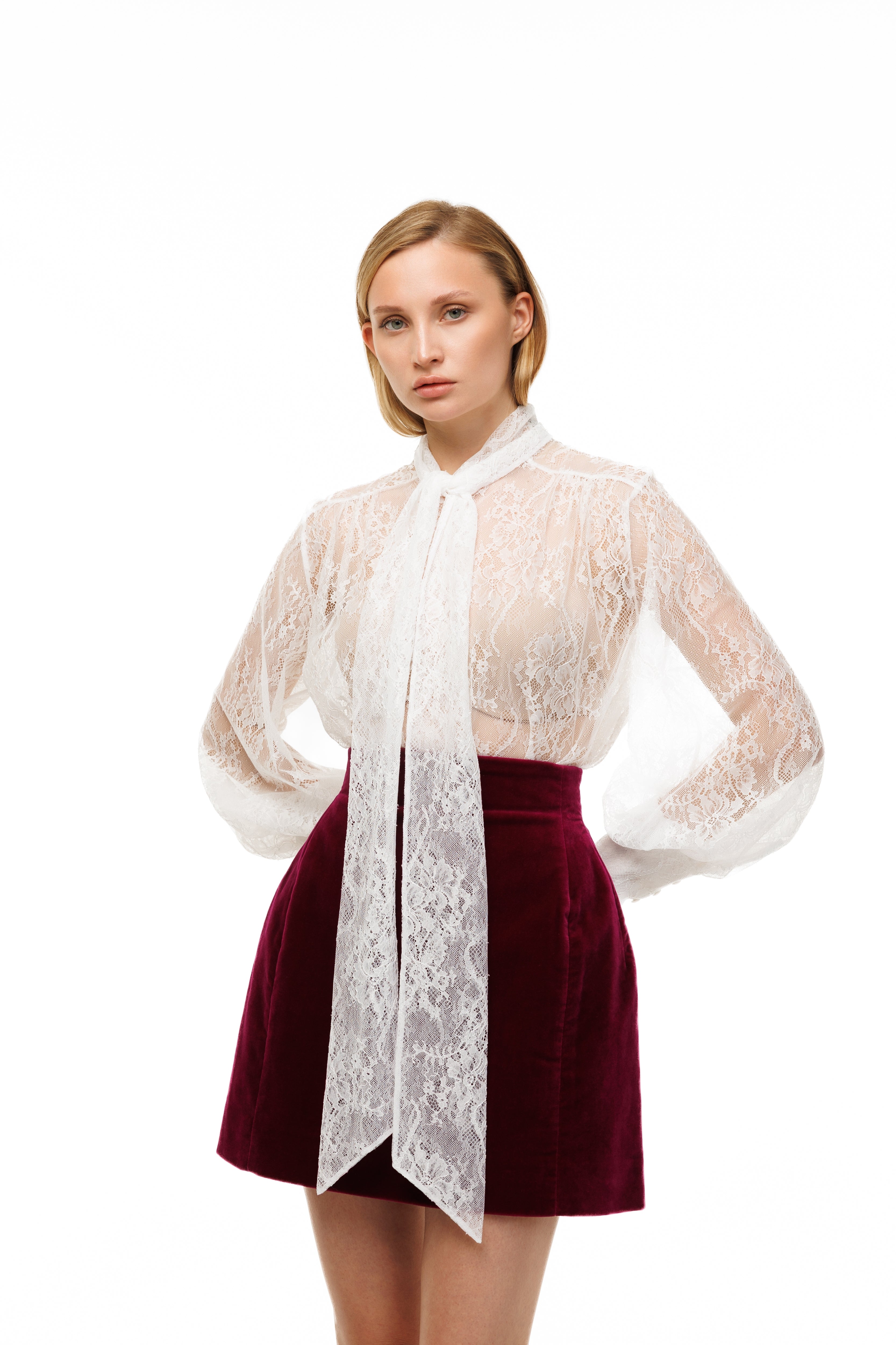 Woman wearing a white lace blouse and red skirt on a white background