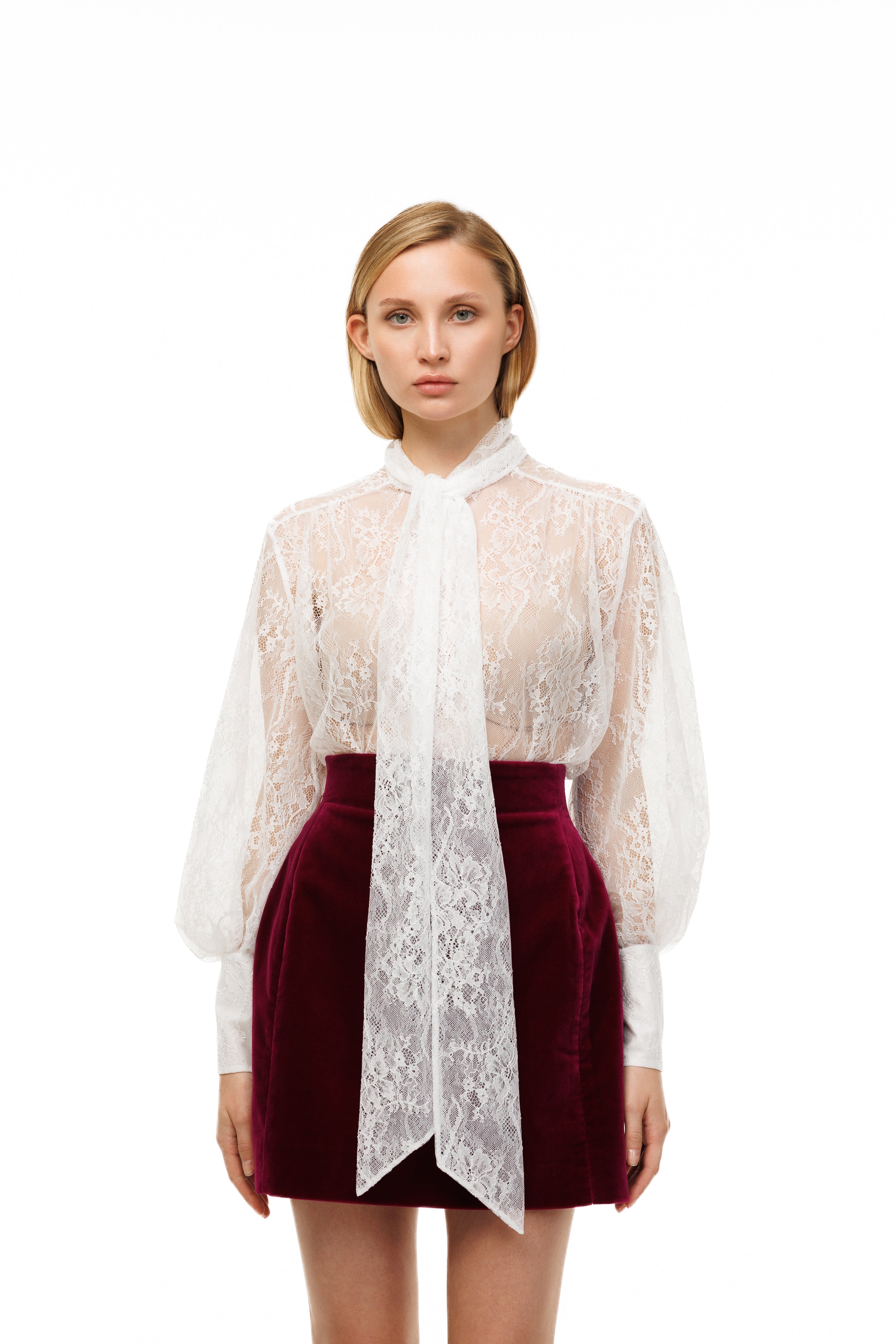 Woman wearing a white lace blouse and red skirt on a white background