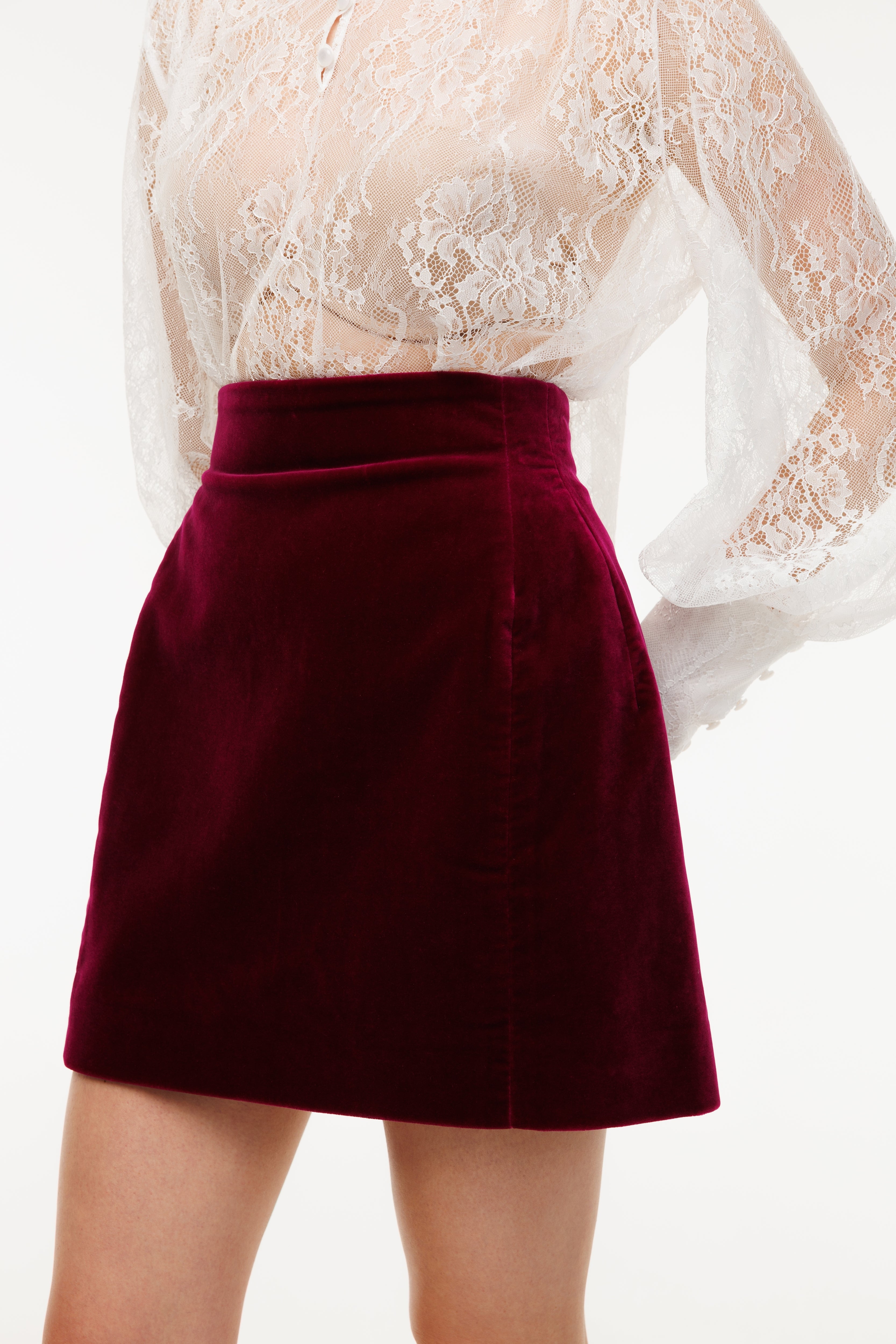 Maroon skirt worn with a white lace top on a white background