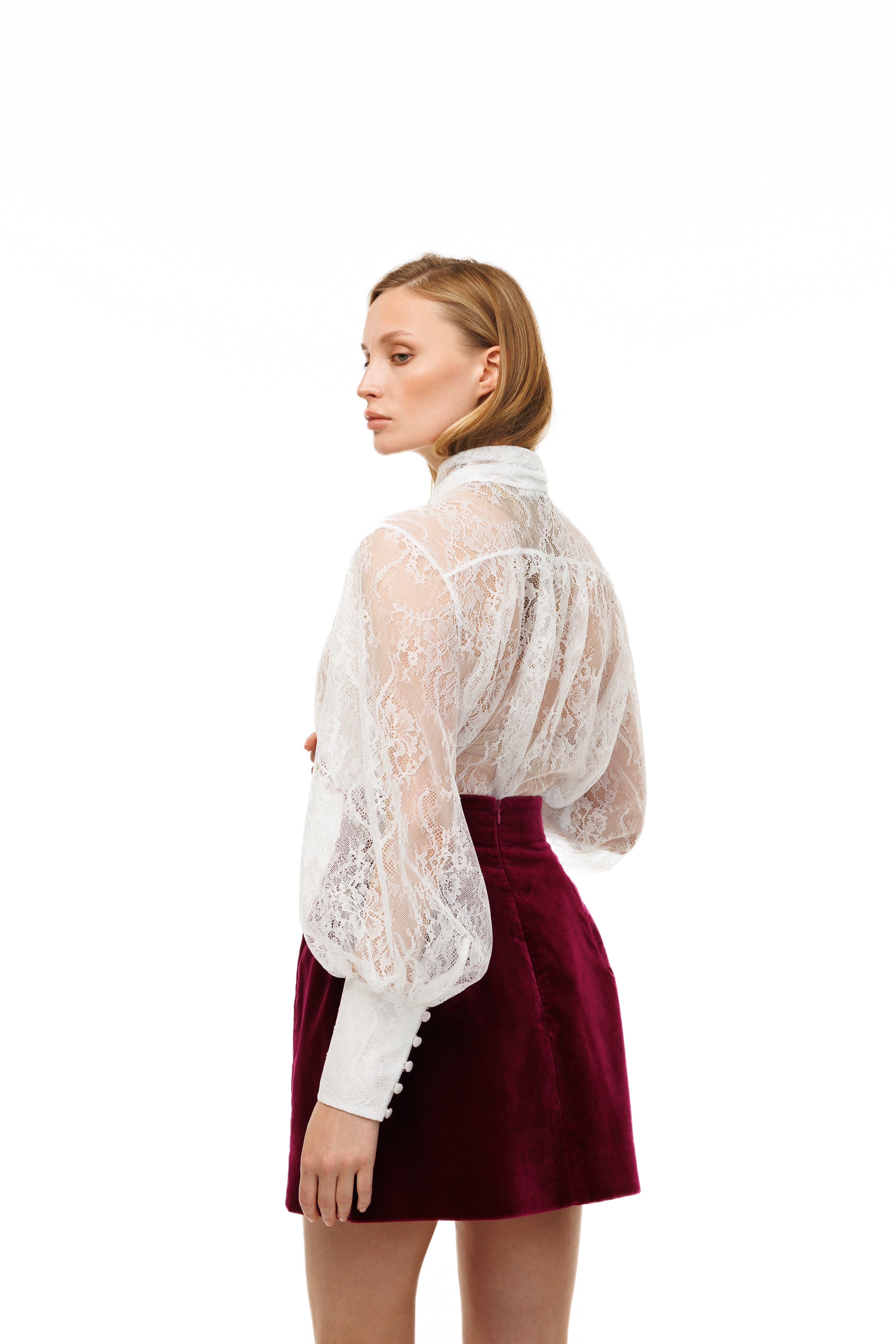 Woman wearing a white lace blouse and red skirt on a white background