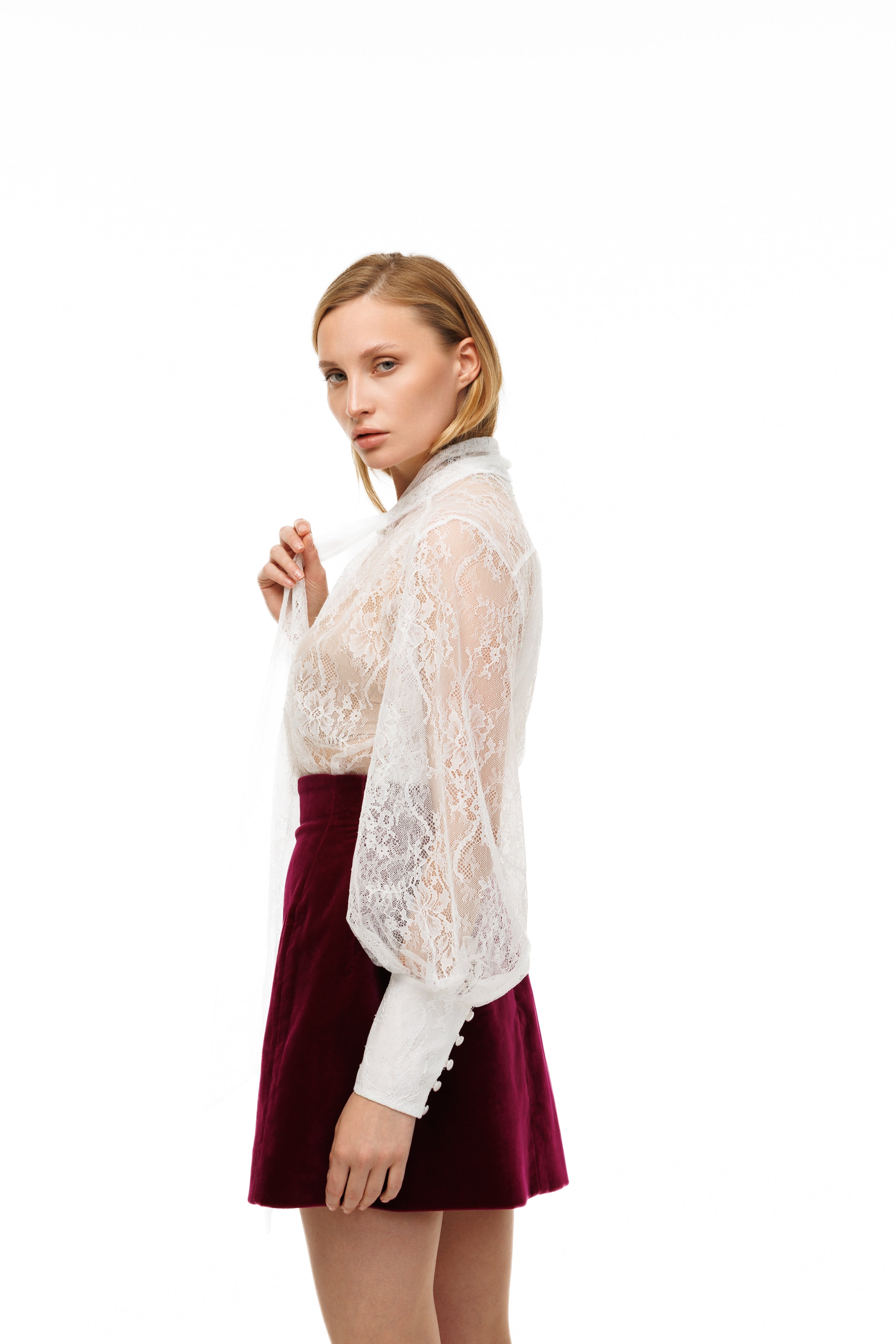 Woman wearing a white lace top and red skirt on a white background