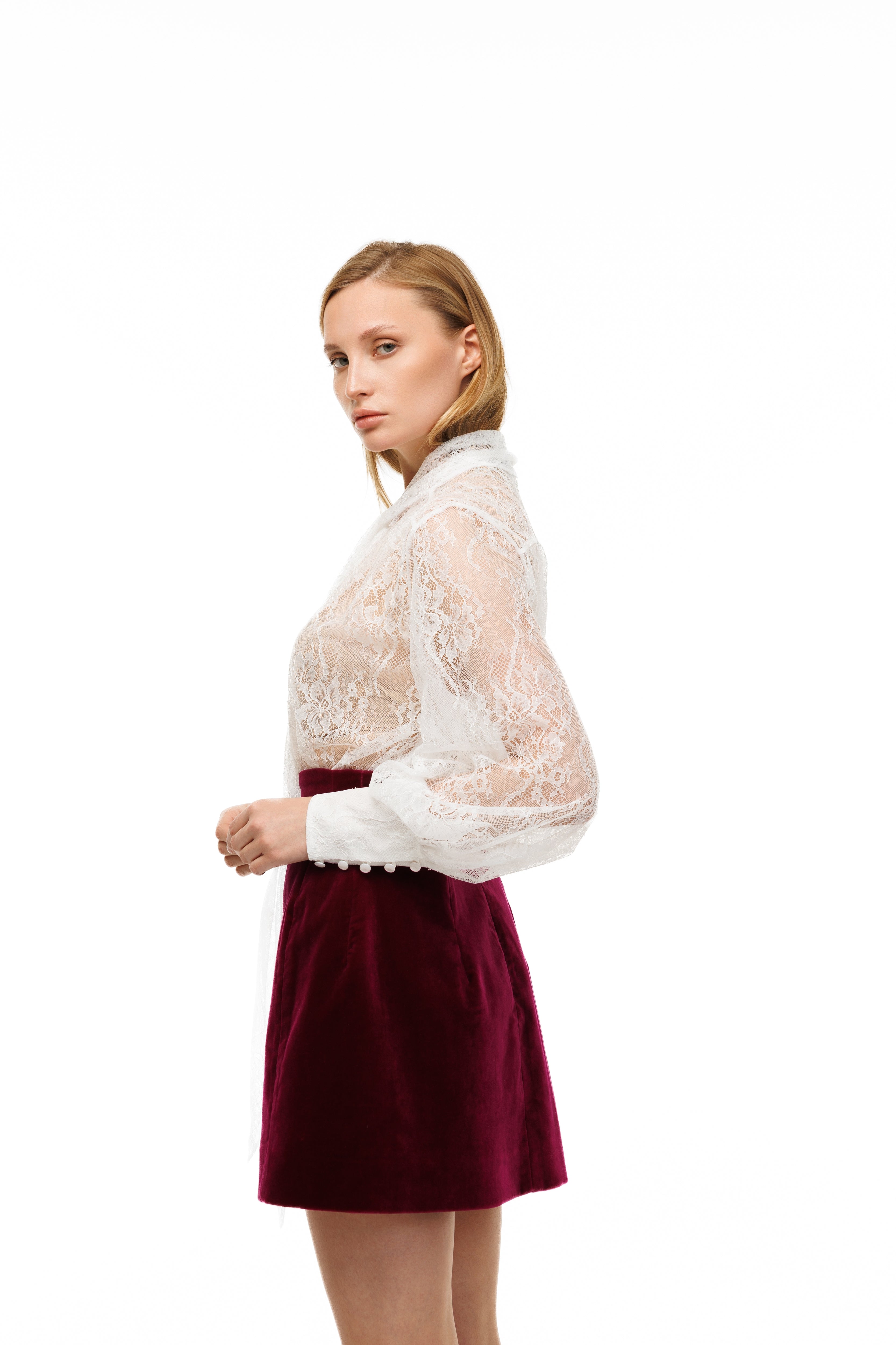 Woman wearing a white lace top and red skirt on a white background