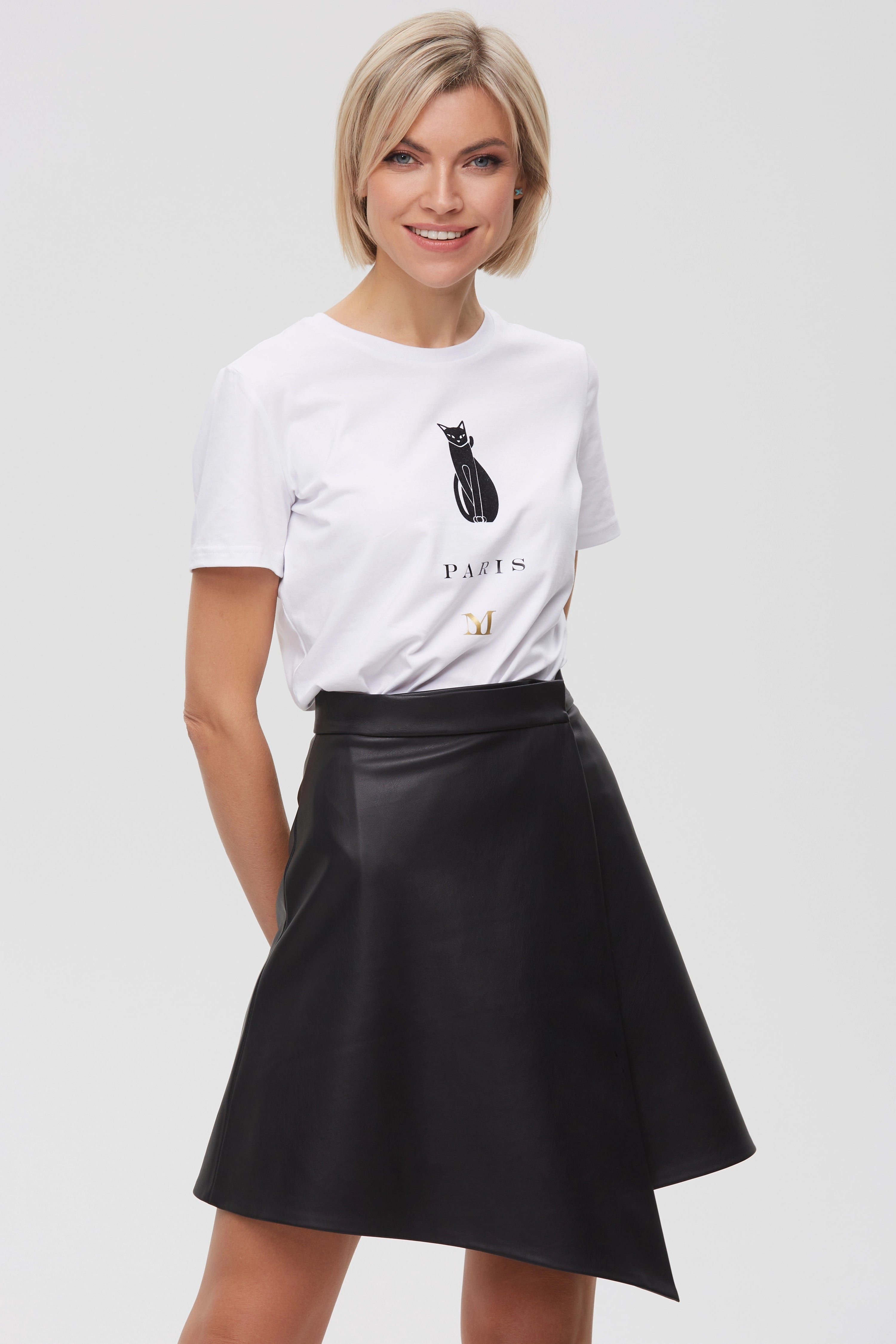 Woman wearing Skirt “Ligne” from Mimaussy Paris, black skirt with white t-shirt featuring black cat graphic and text on light gray background