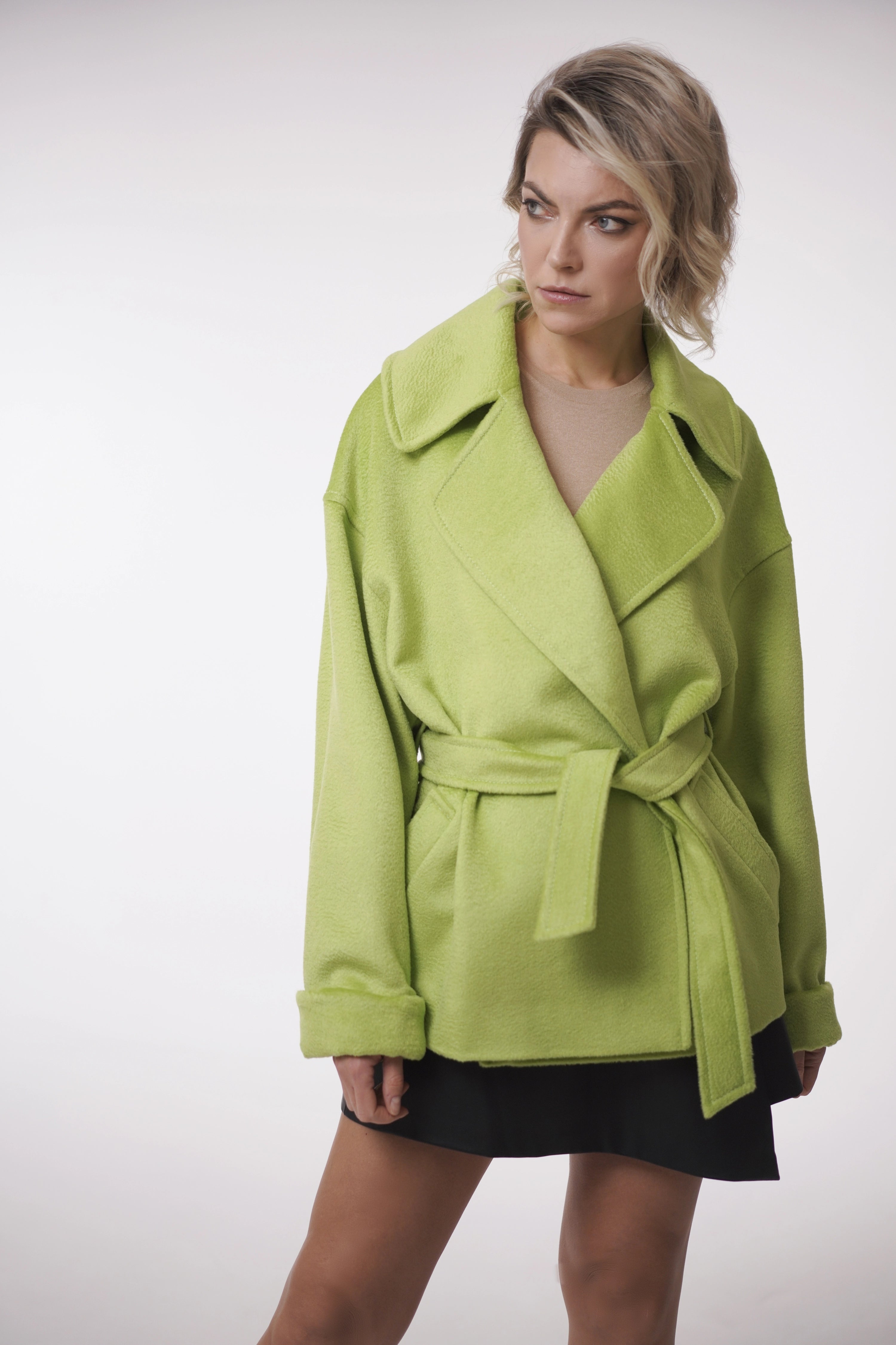Woman wearing Spring Touch Coat from Mimaussy Paris, bright green coat against a white background, studio setting