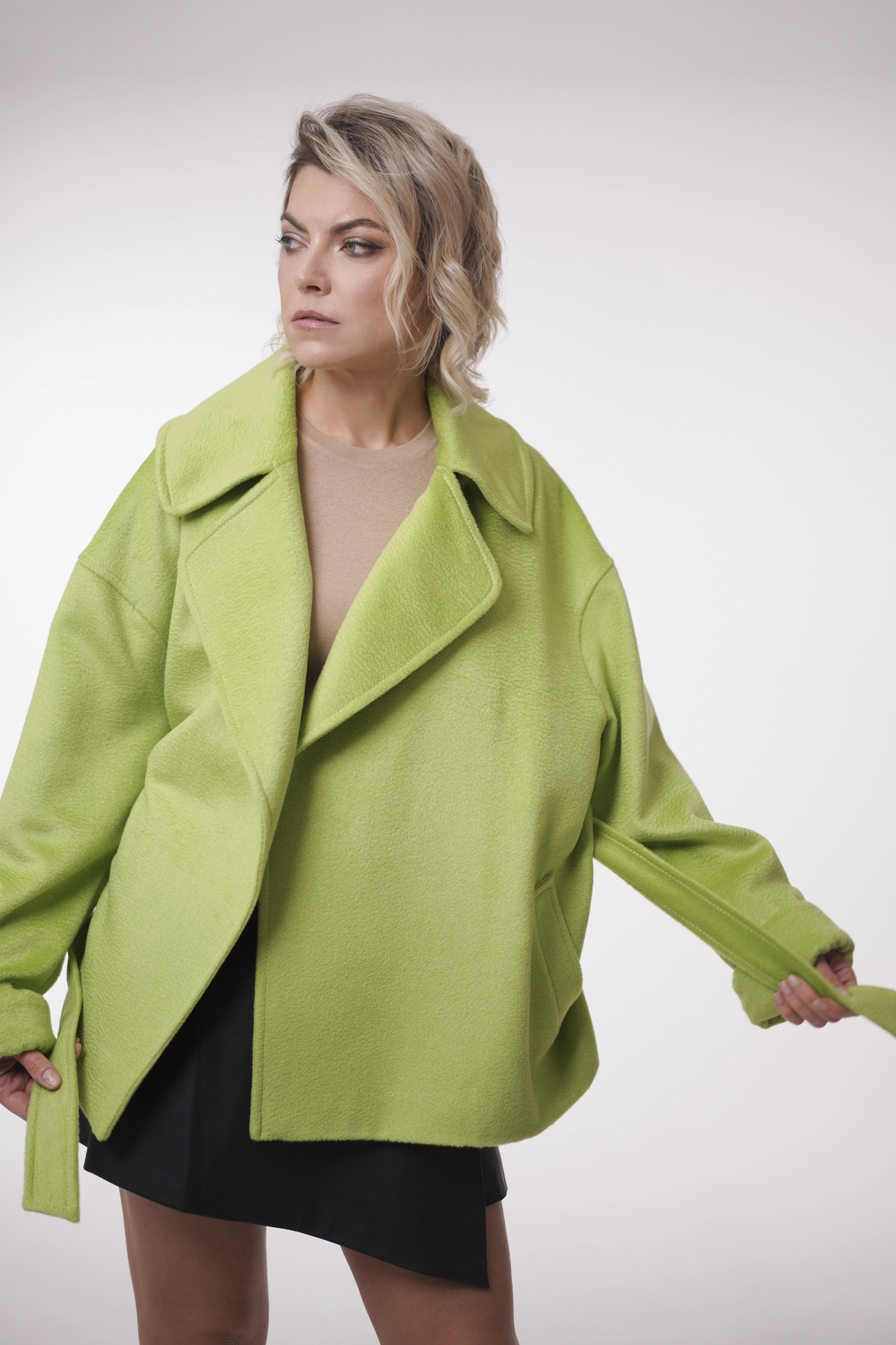 Woman wearing Spring Touch Coat from Mimaussy Paris, bright green coat against a white background, studio setting