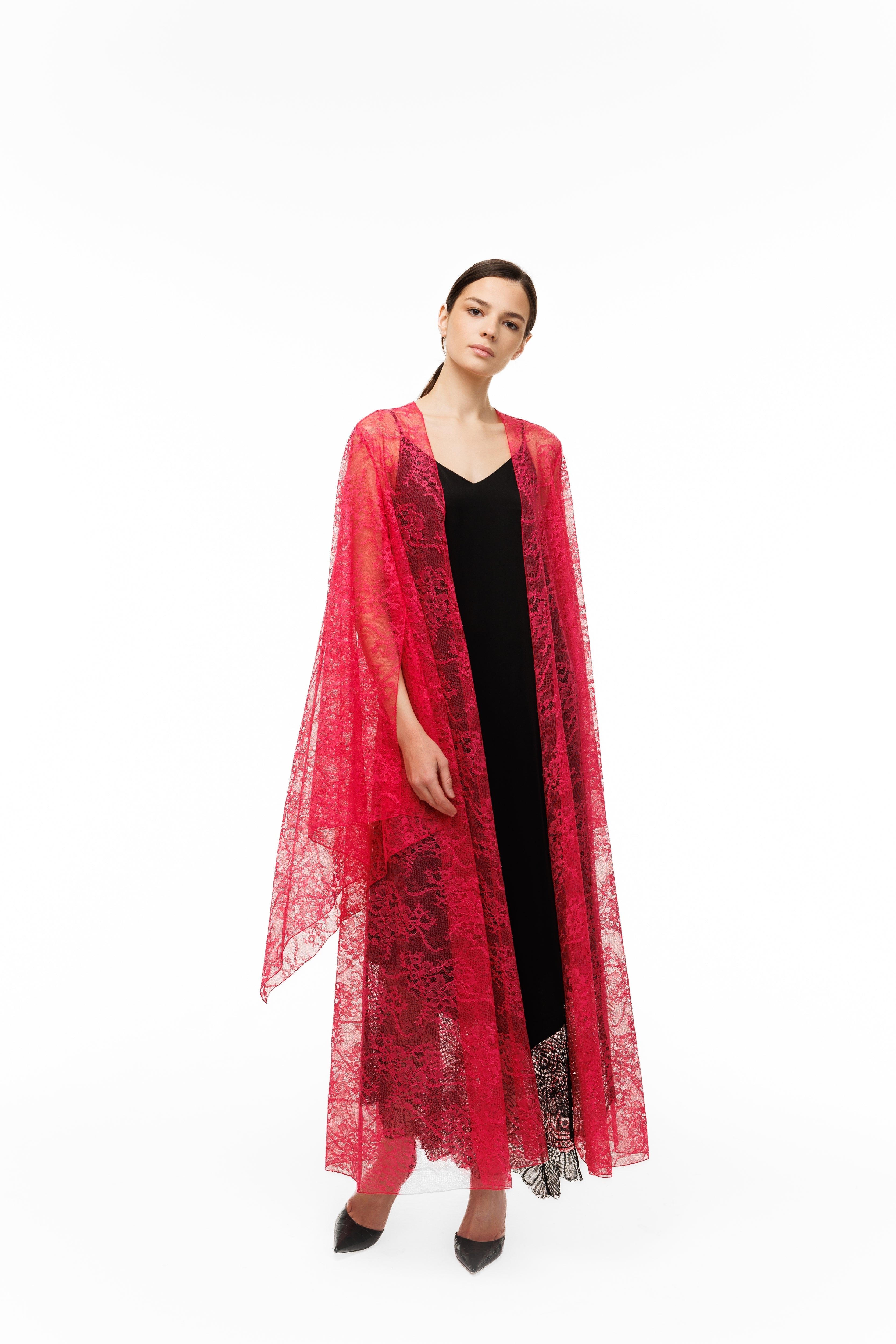A woman in a red lace cape over a black dress on a white background