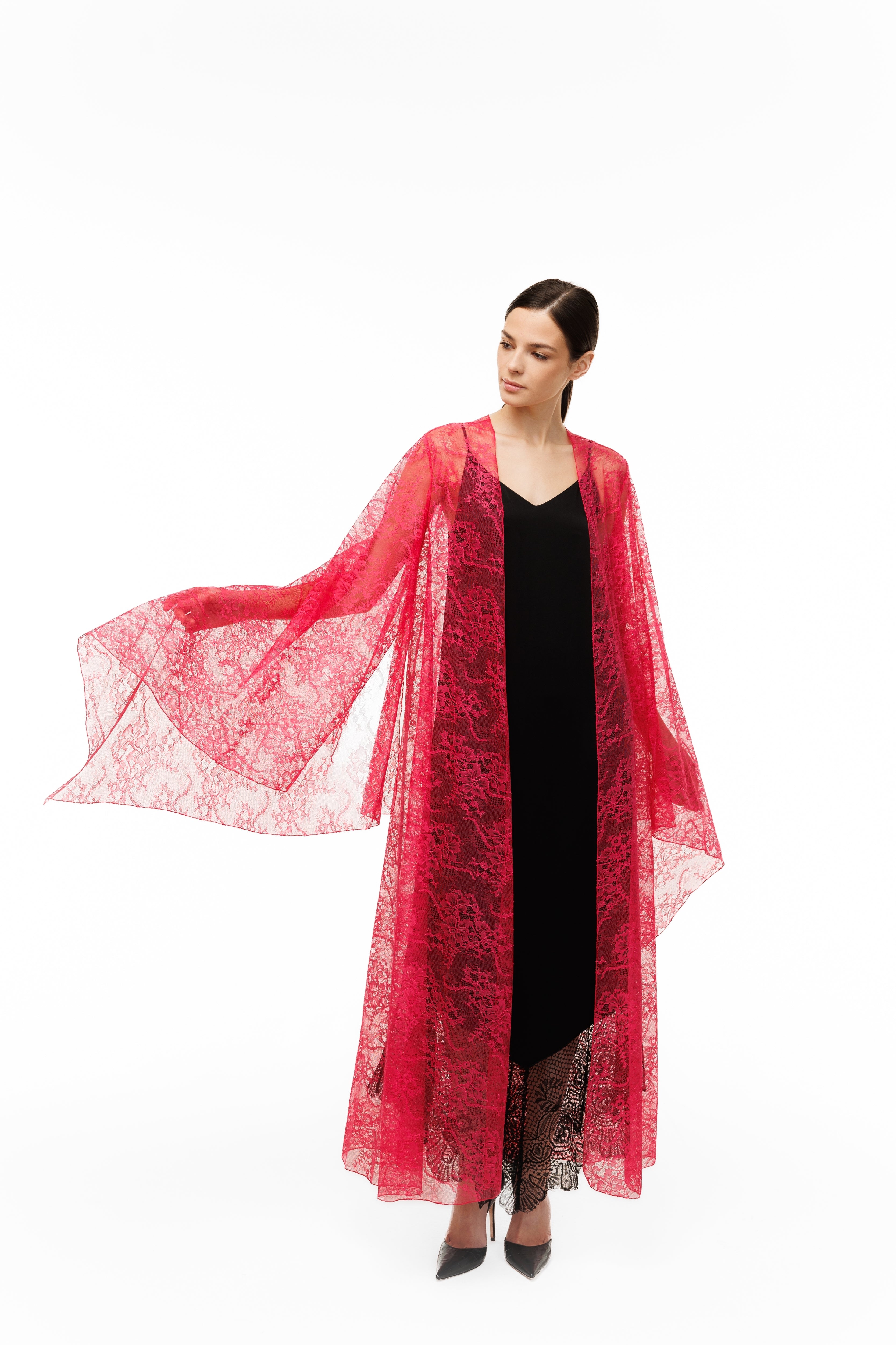 A woman in a red lace cape over a black dress on a white background
