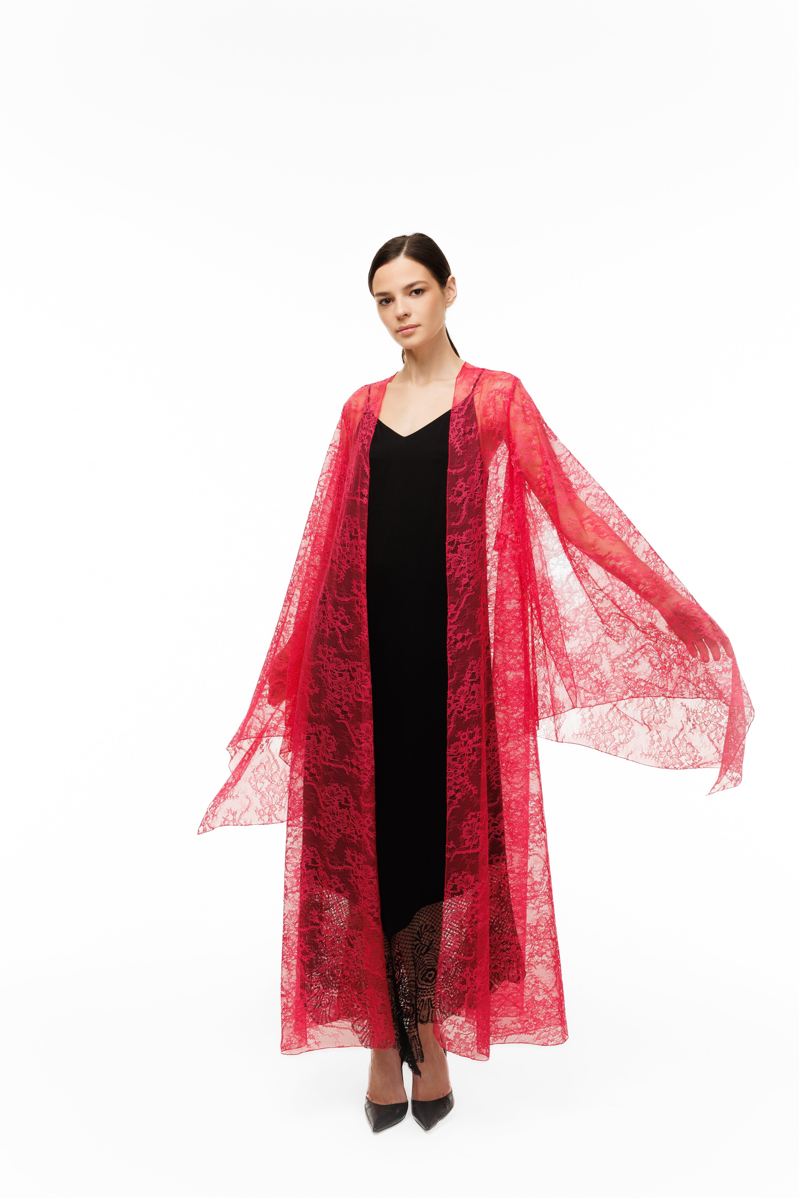 Woman wearing a red lace garment over a black dress on a white background