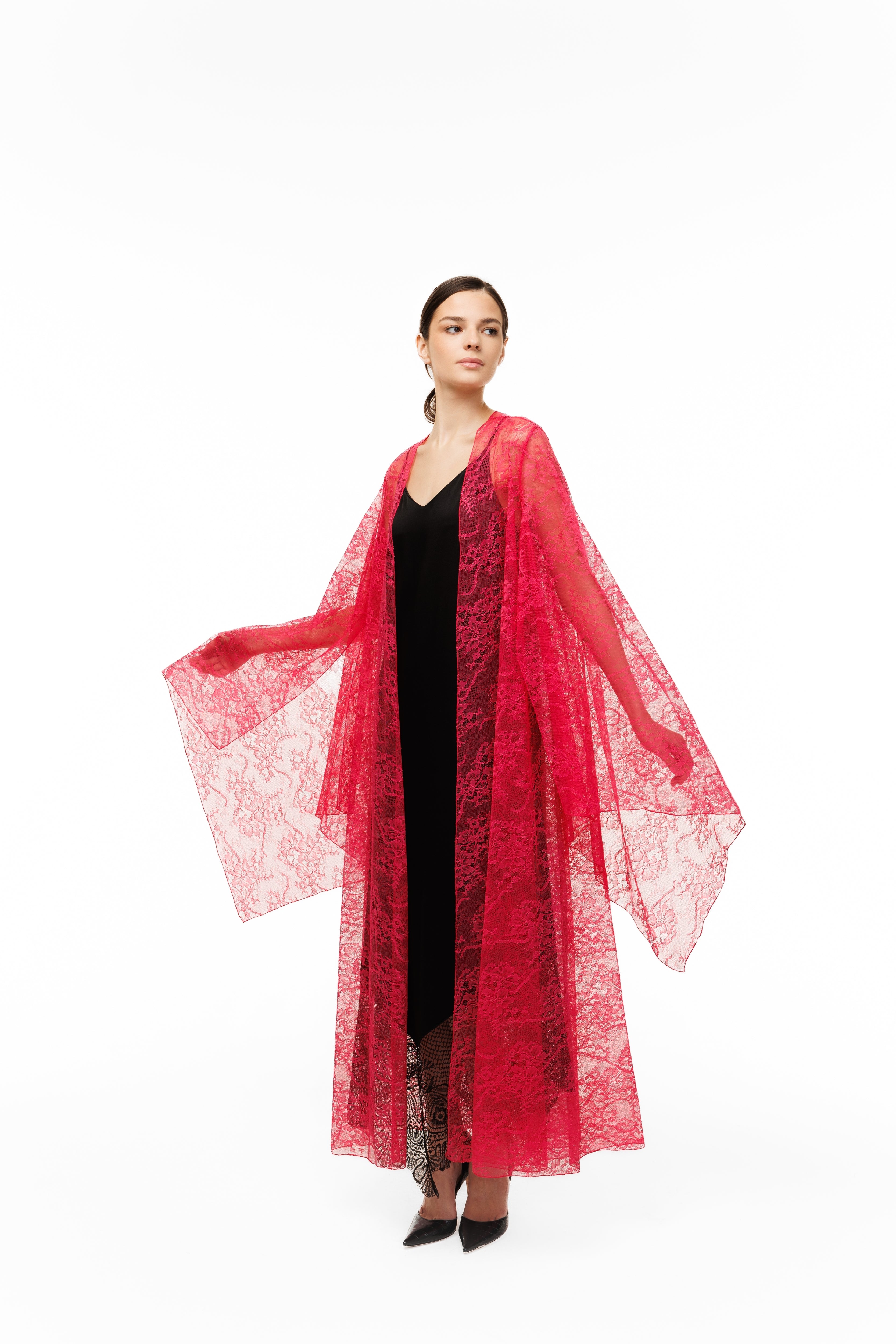 Woman wearing a red cape over a black dress on a white background