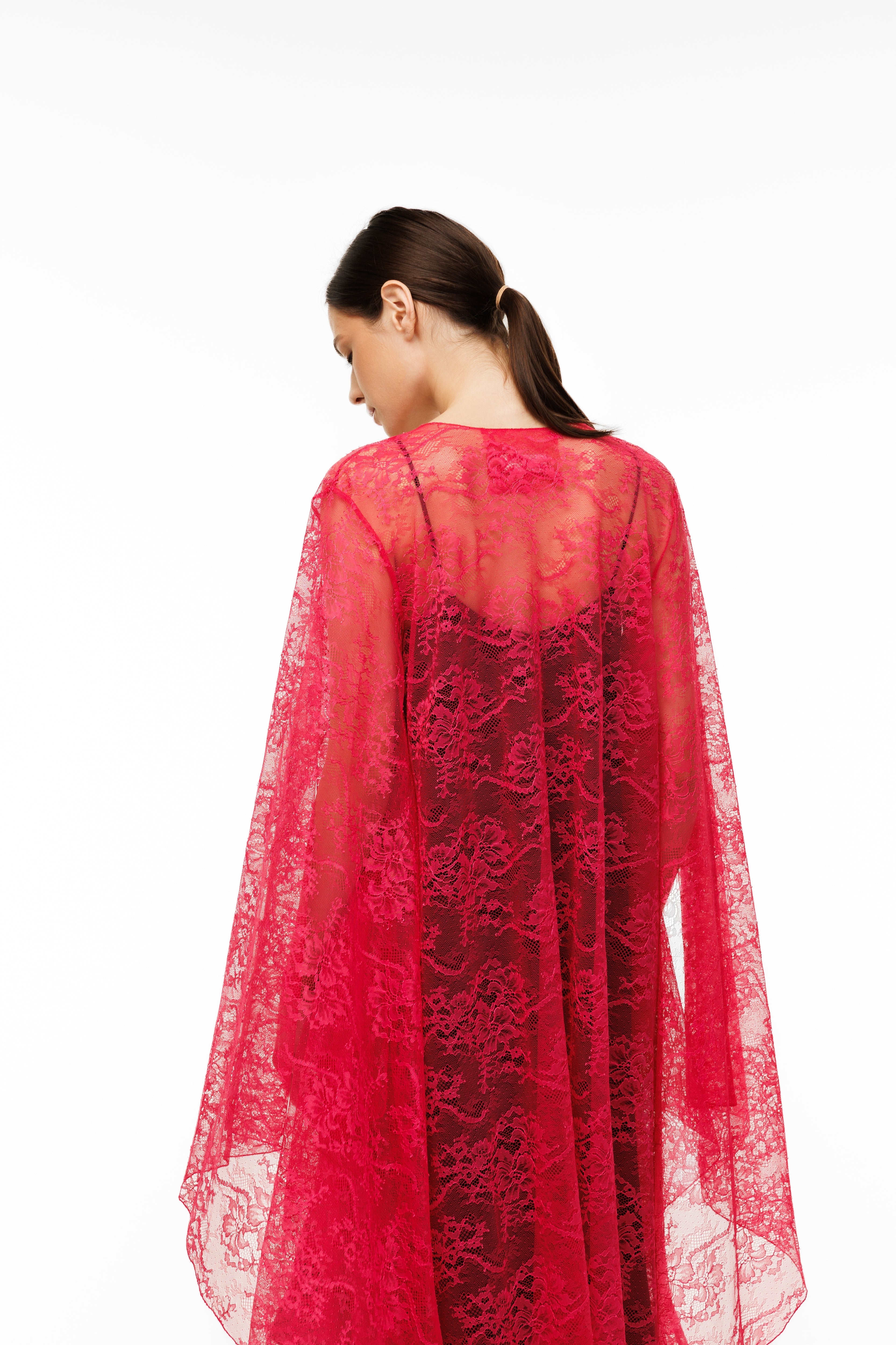 Woman wearing a red cape over a black dress on a white background