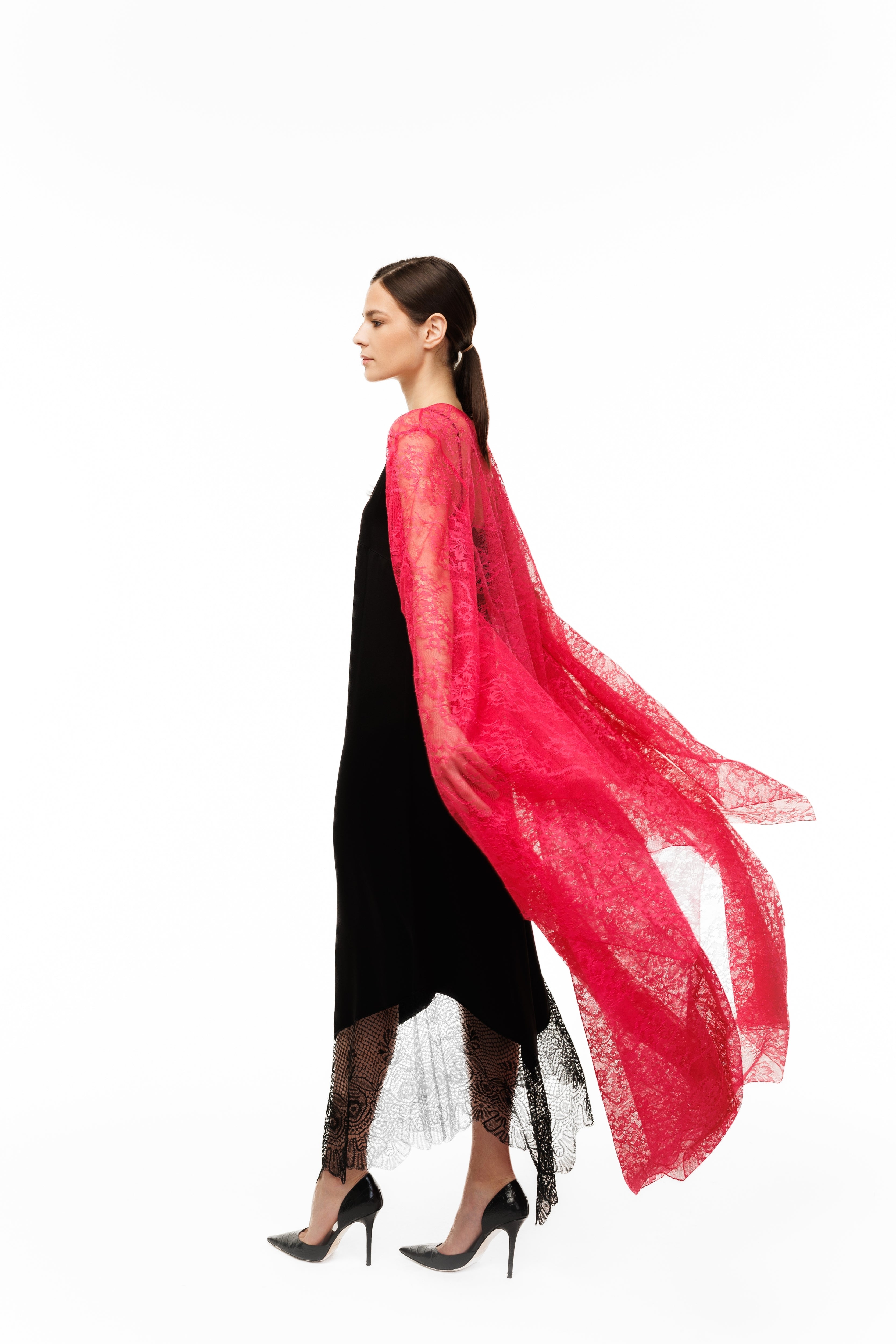A woman in a red lace cape over a black dress on a white background