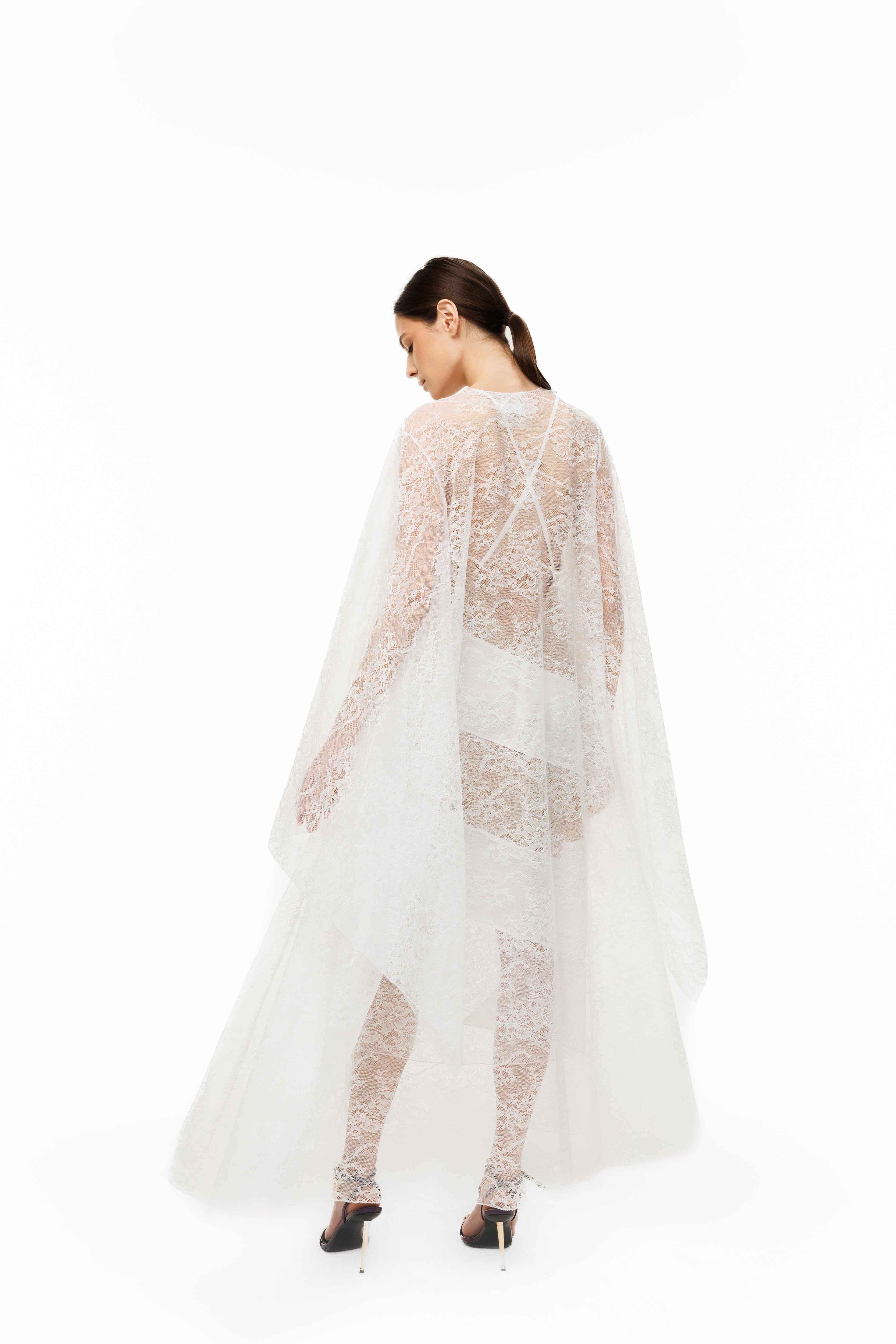 Woman wearing a sheer white lace dress on a white background
