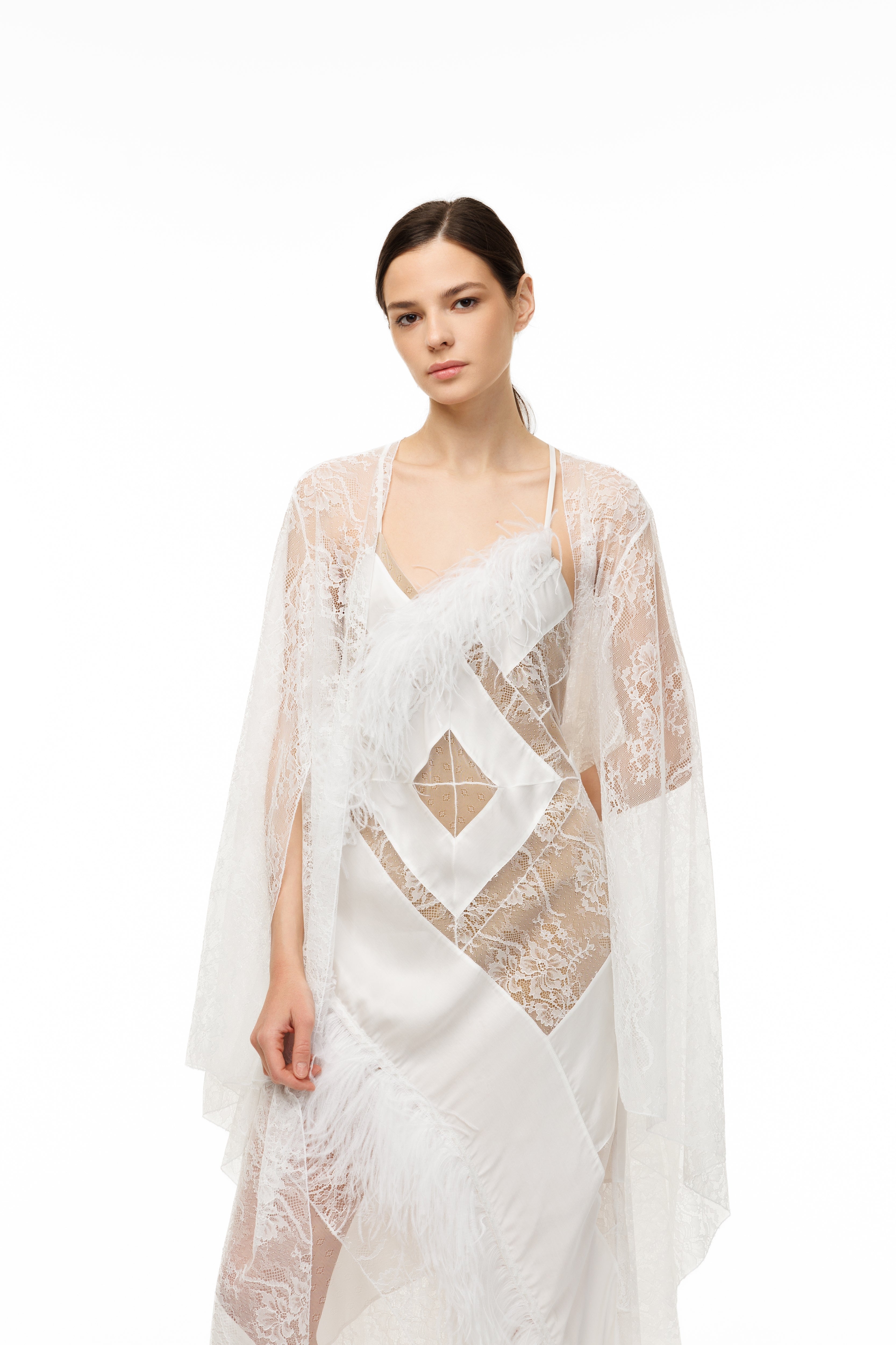 Woman wearing a white lace dress with a sheer overlay on a white background