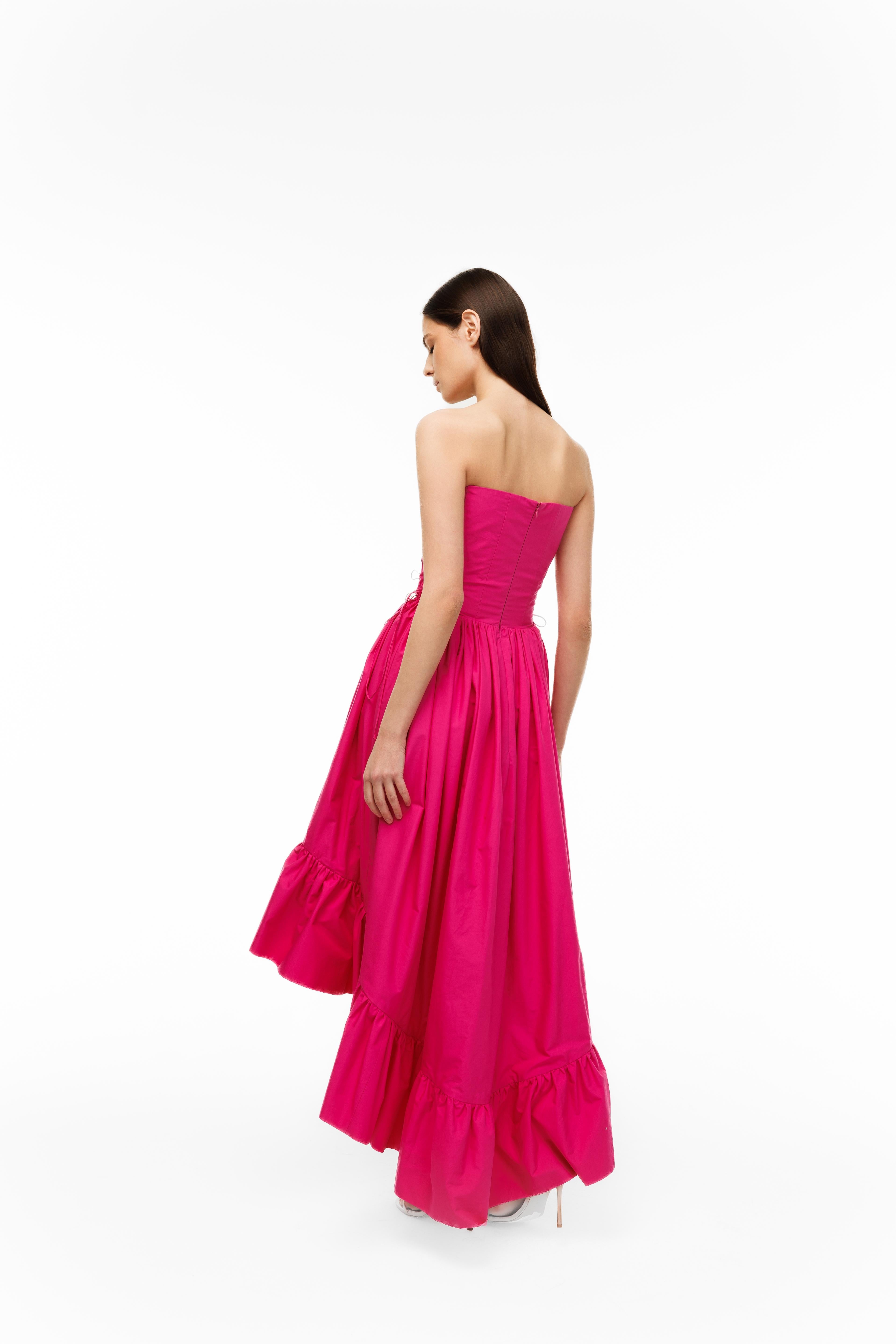 Woman wearing a bright pink strapless gown on a white background