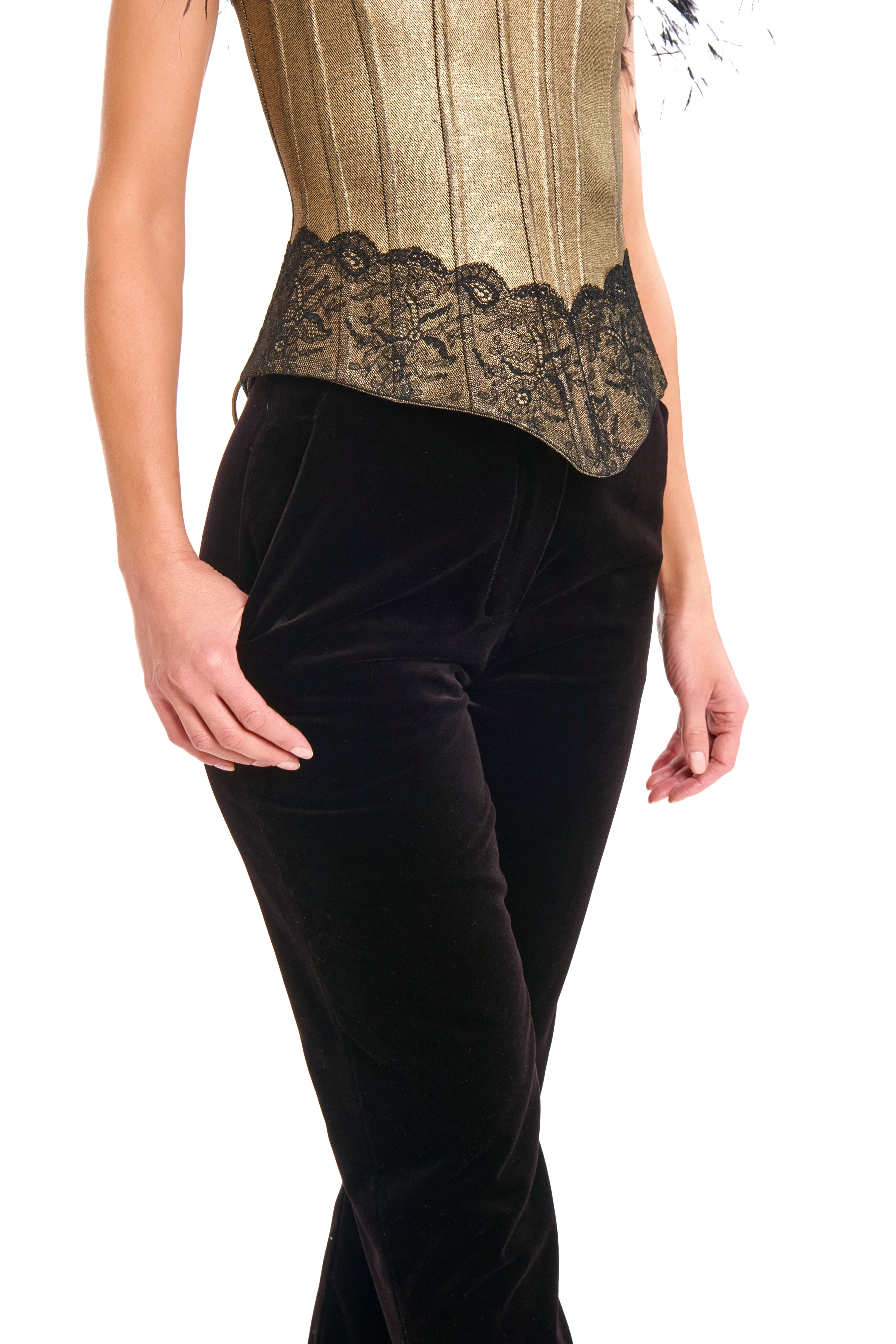 Woman wearing Velvet trousers from Mimaussy Paris, close-up front view of black velvet pants with gold strapless top with feather details on white background