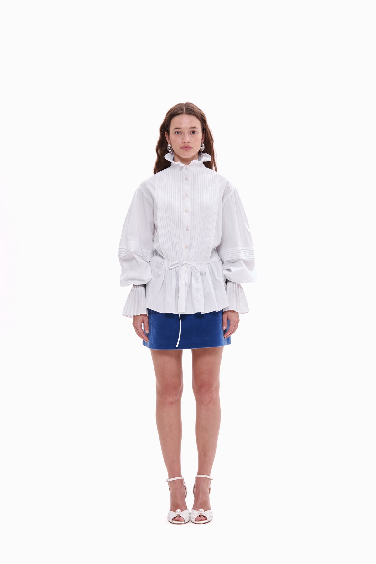 Person wearing a white textured top and blue skirt on a white background